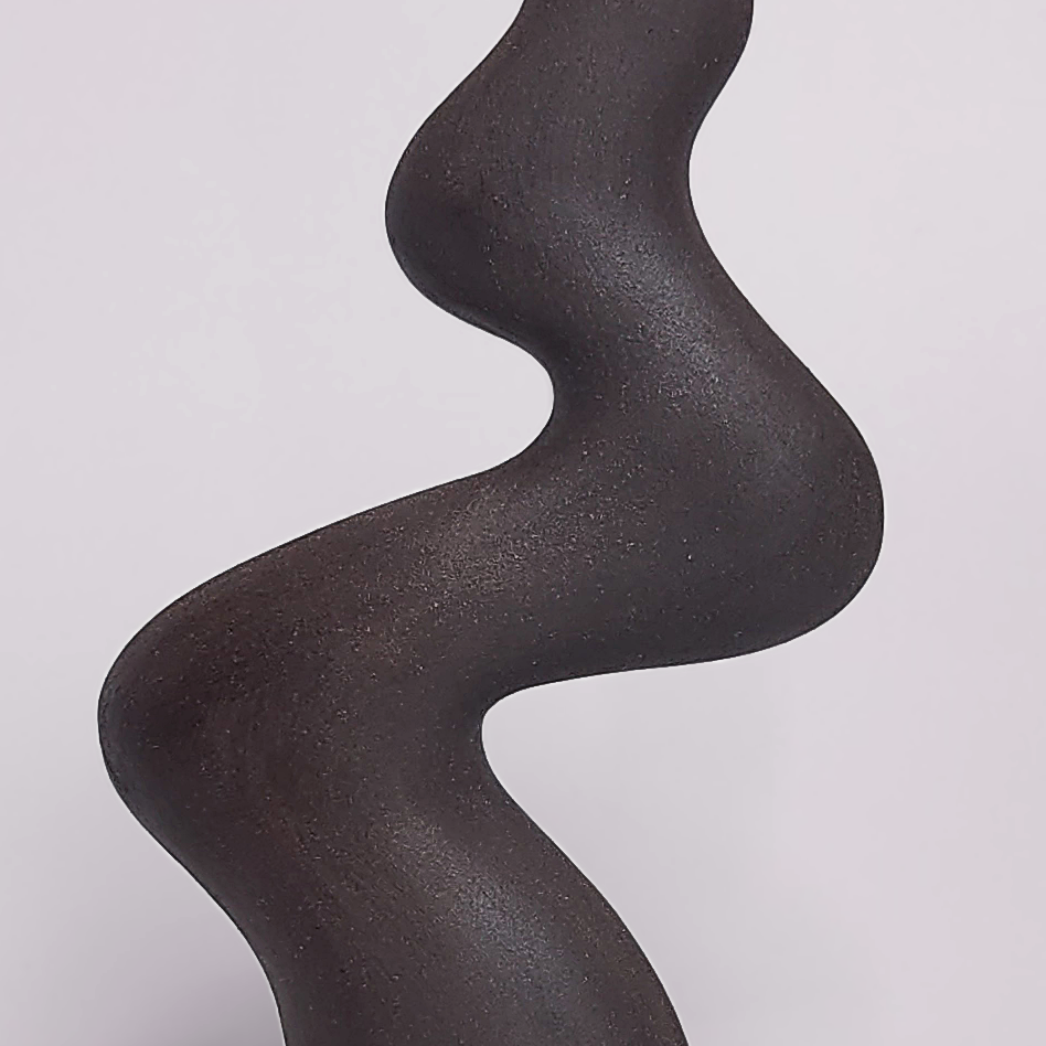 minimalist black handmade ceramic candle holder for a single candle, crafted in an elegant organic curved shape