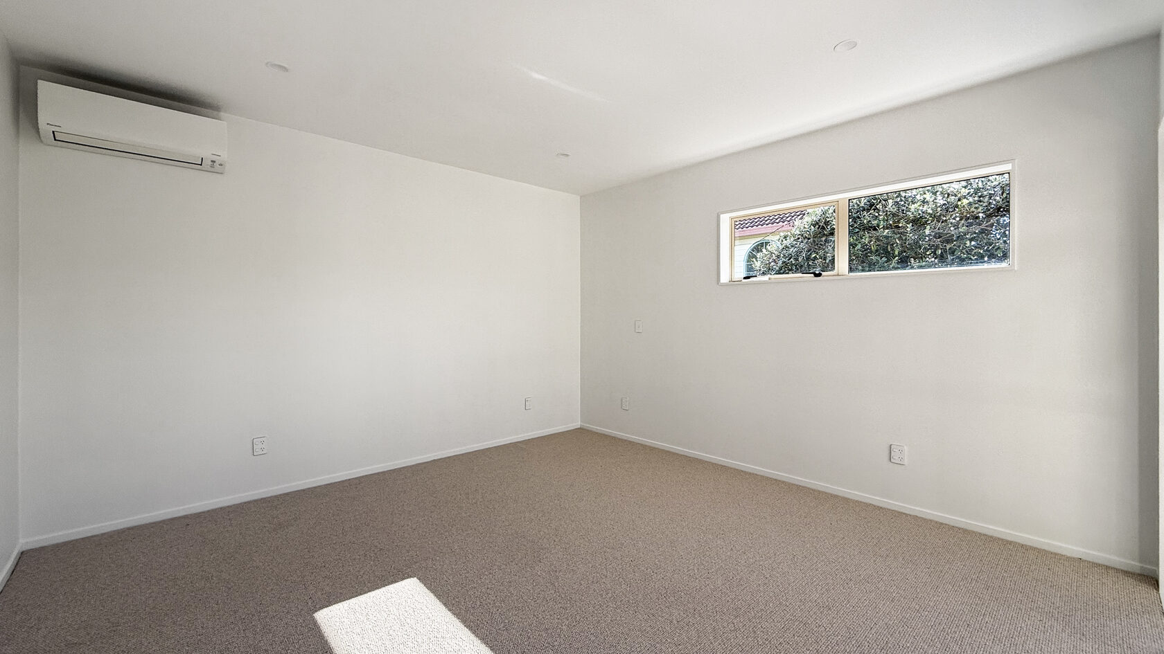 Renovated St Heliers bedroom with new carpet, recessed lights and wall-mounted heat pump.