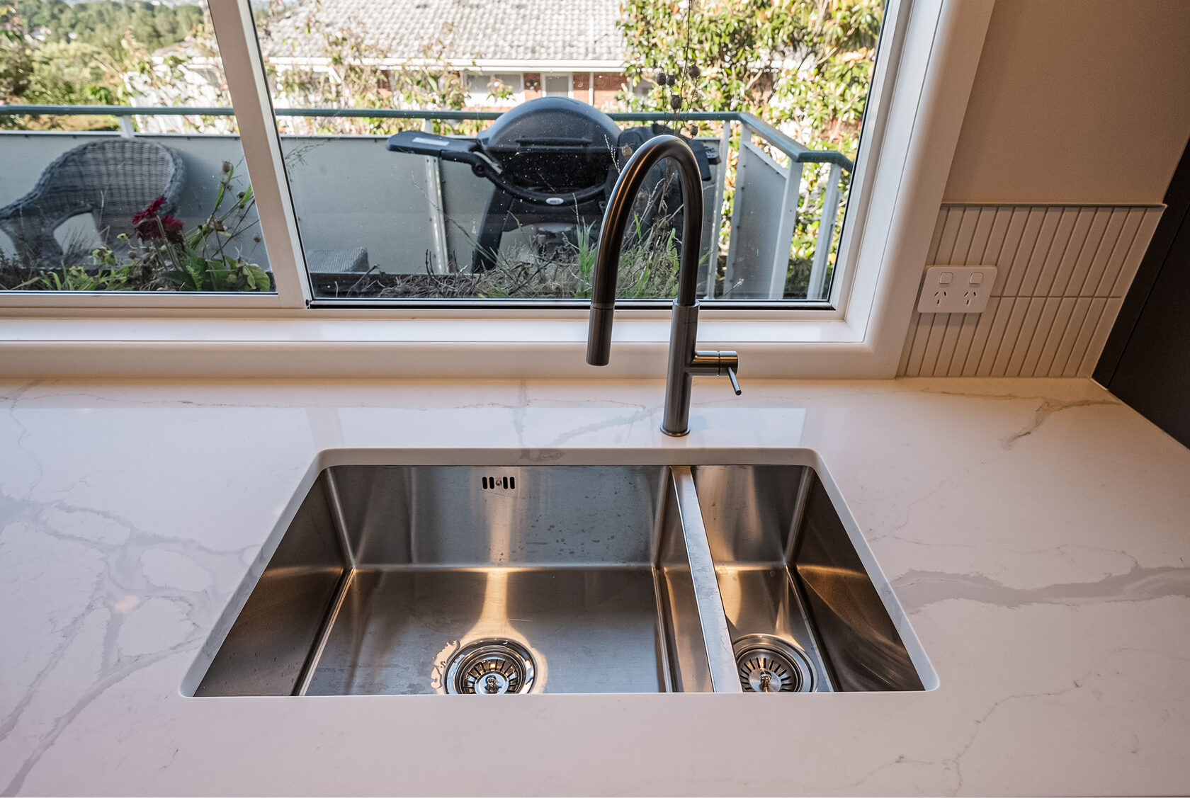 Double stainless-steel sink and black tap beneath the Glenfield kitchen window
