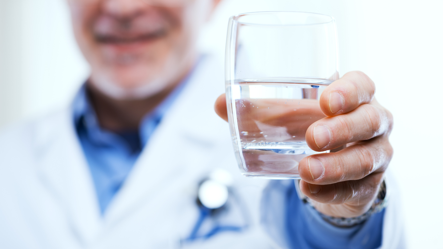 The image shows a doctor holding a glass of purified water, symbolizing a scientific and balanced perspective on the potential concerns and benefits of reverse osmosis