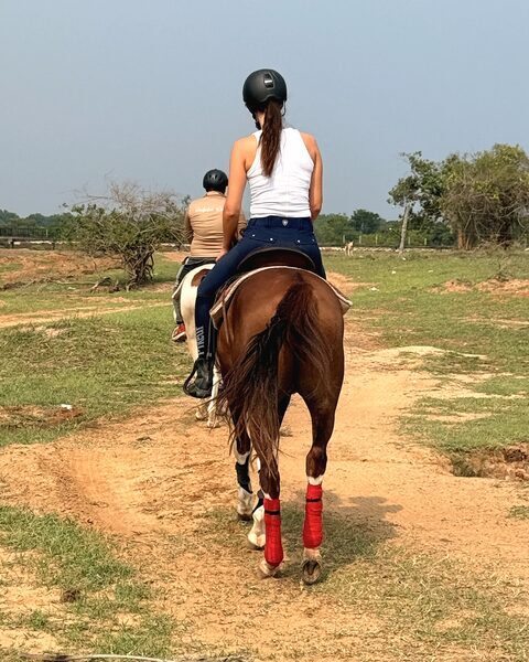 A rider on the red-earth track at Punanai with a Ranch guide riding ahead.