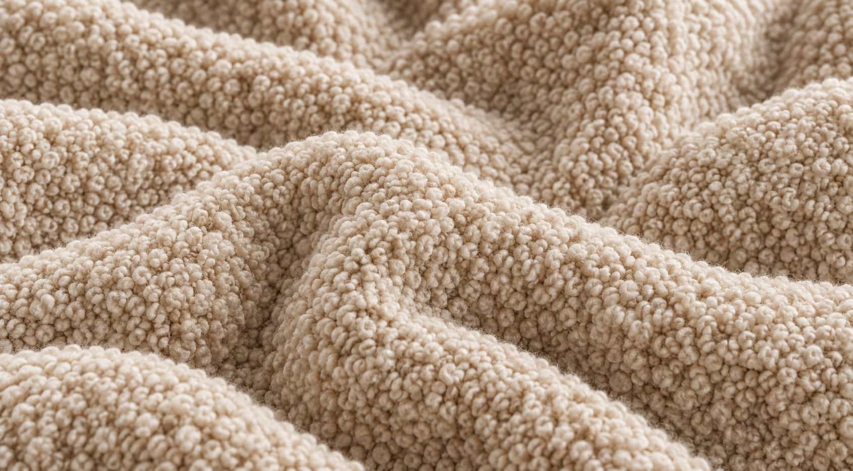Nahaufnahme eines cremewei&szlig;en Boucl&eacute;-Stoffs mit kleinen Garnschlingen, zwischen denen sich Staub und Haare festsetzen. Shikardos Reinigung reinigt Boucl&eacute;-Sofas in Frankfurt ohne B&uuml;rste und mit geringem Druck.