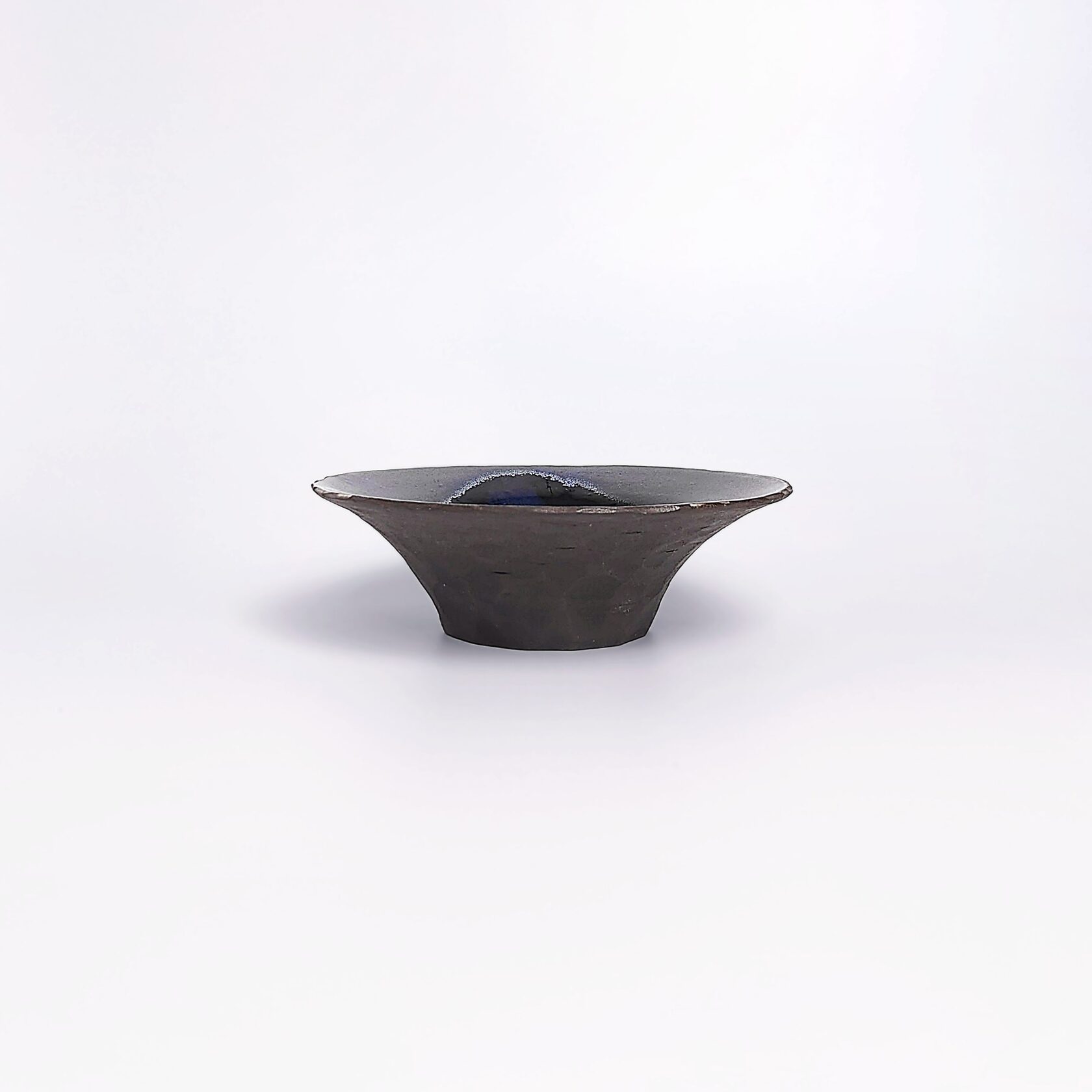 Handmade decorative ceramic plate with deep blue glossy glaze and black clay base