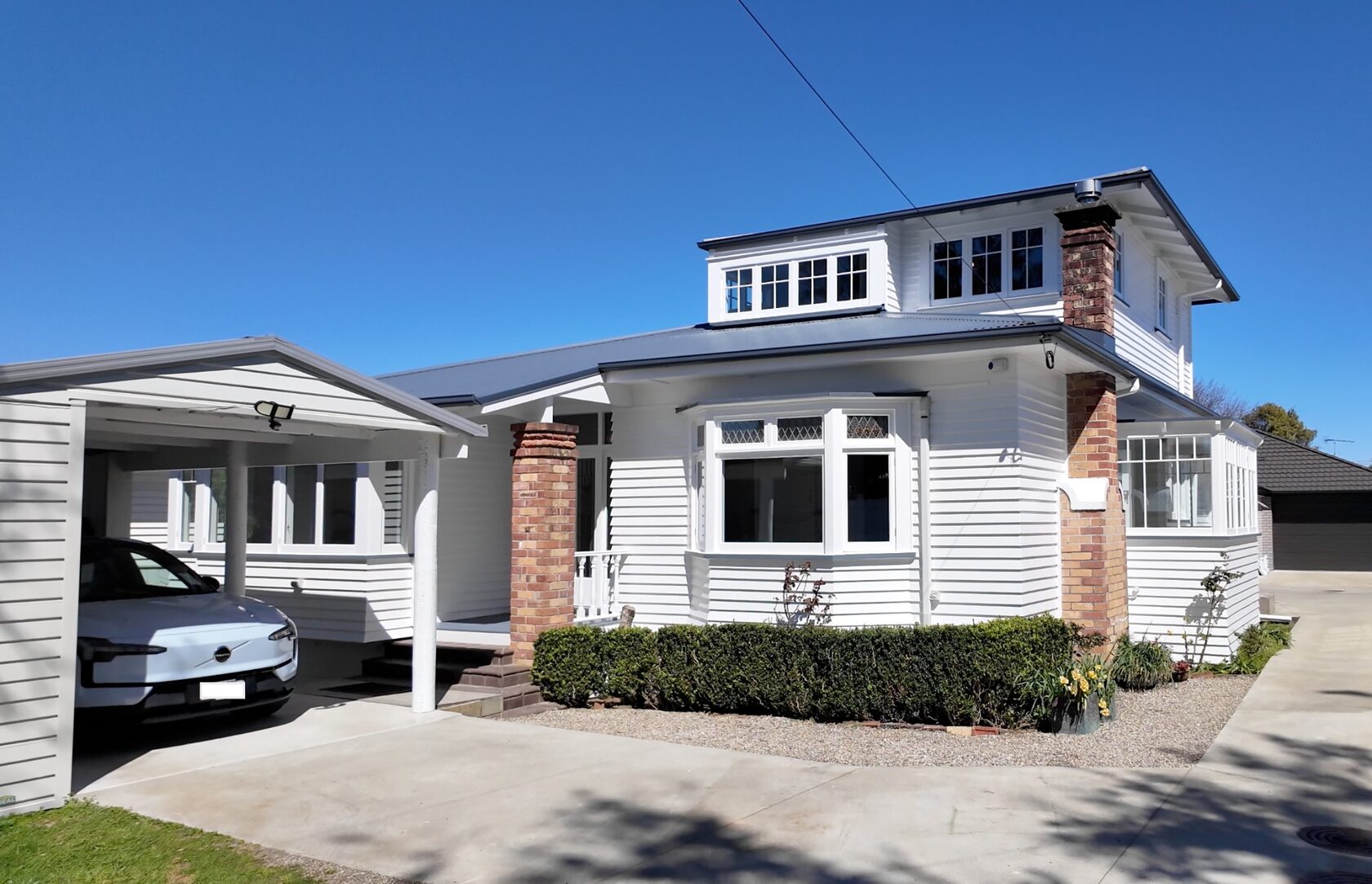 Exterior of the Hollywood Avenue bungalow in Epsom with white cladding, brick details and a covered driveway