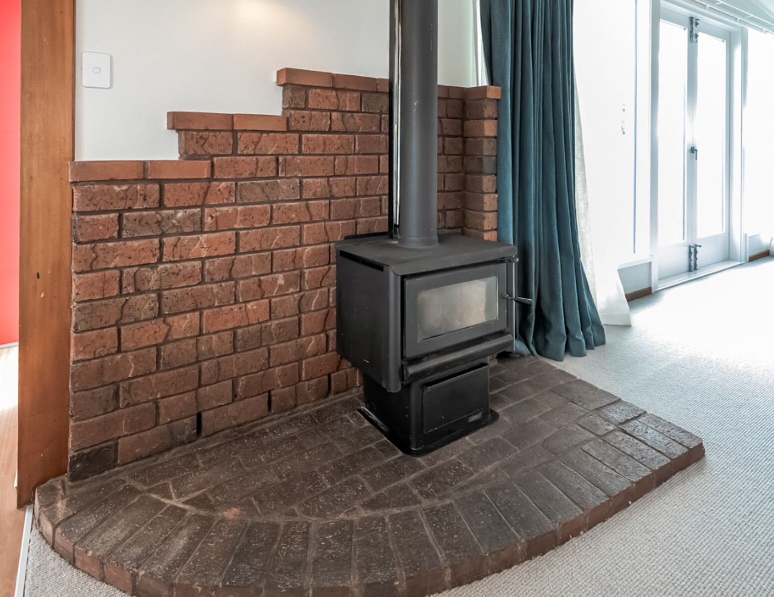 After: retained brick fireplace and black wood burner beside the renovated living area