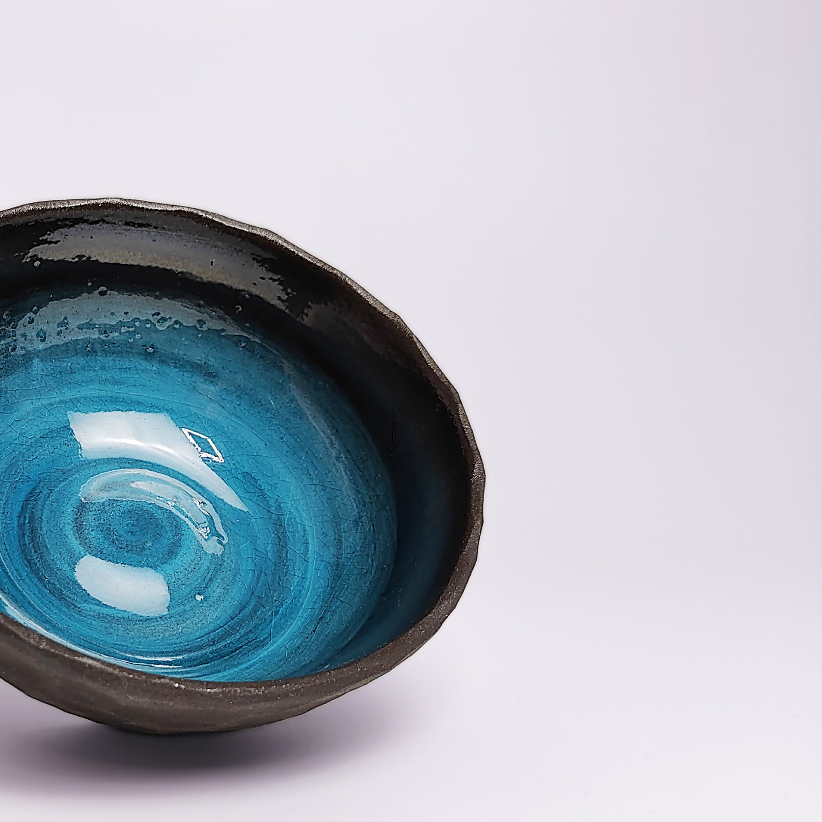 unique handmade ceramic bowl with dark clay exterior and vibrant deep blue glaze, artistic decorative tableware