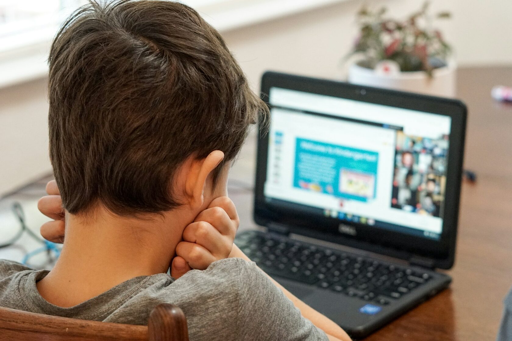 Dziecko w wieku 8 lat uśmiechnięte podczas nauki online przy laptopie