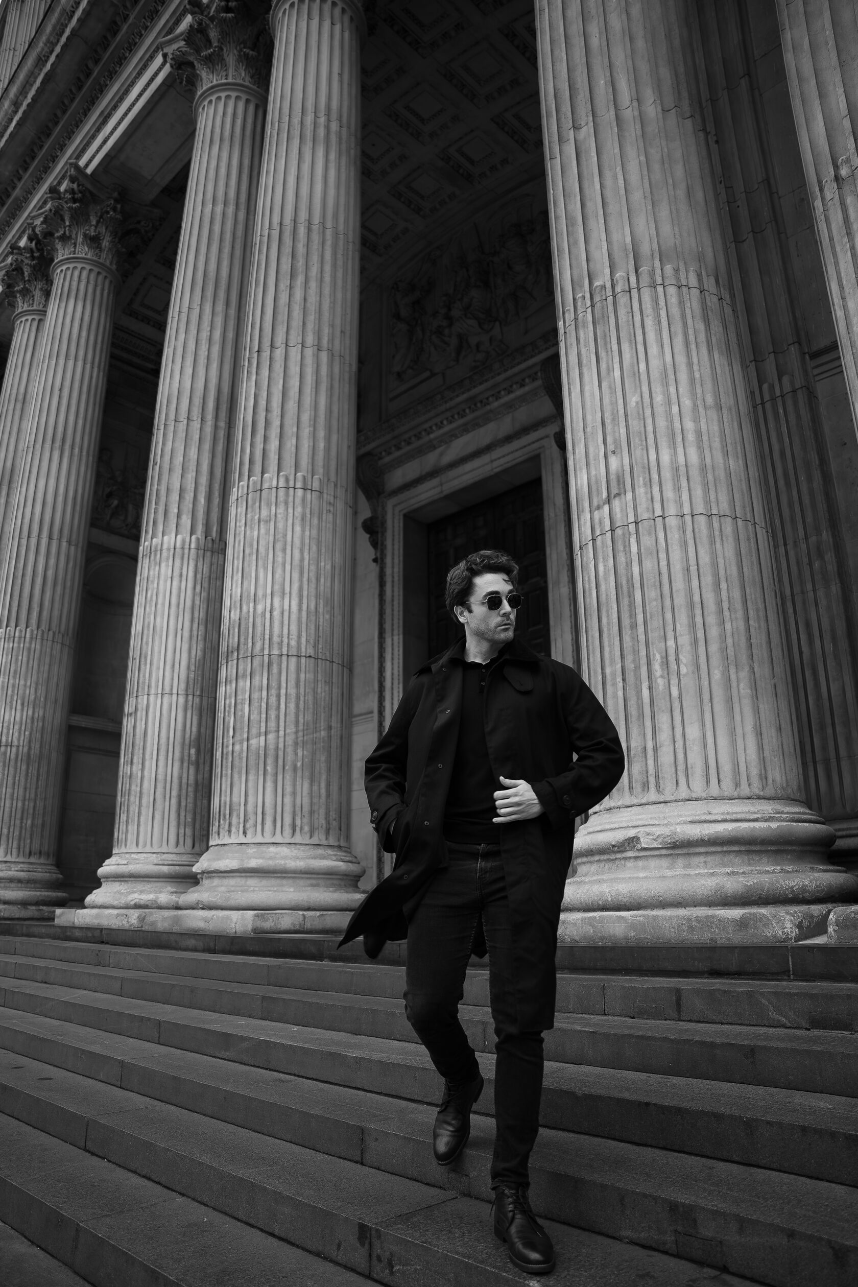 Black-and-white portrait beside monumental stone columns