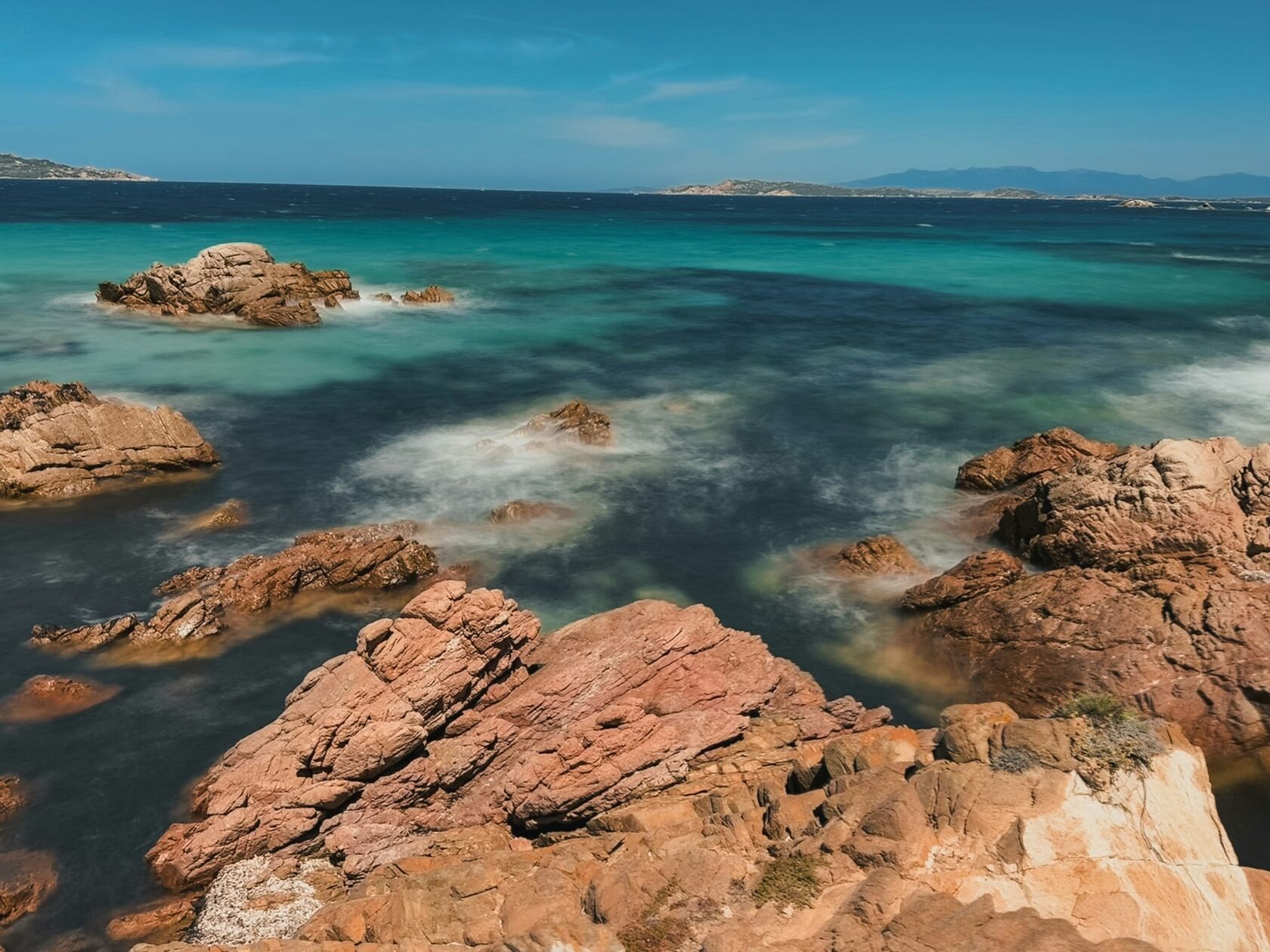 A turquoise cove framed by pink granite rocks in the La Maddalena archipelago