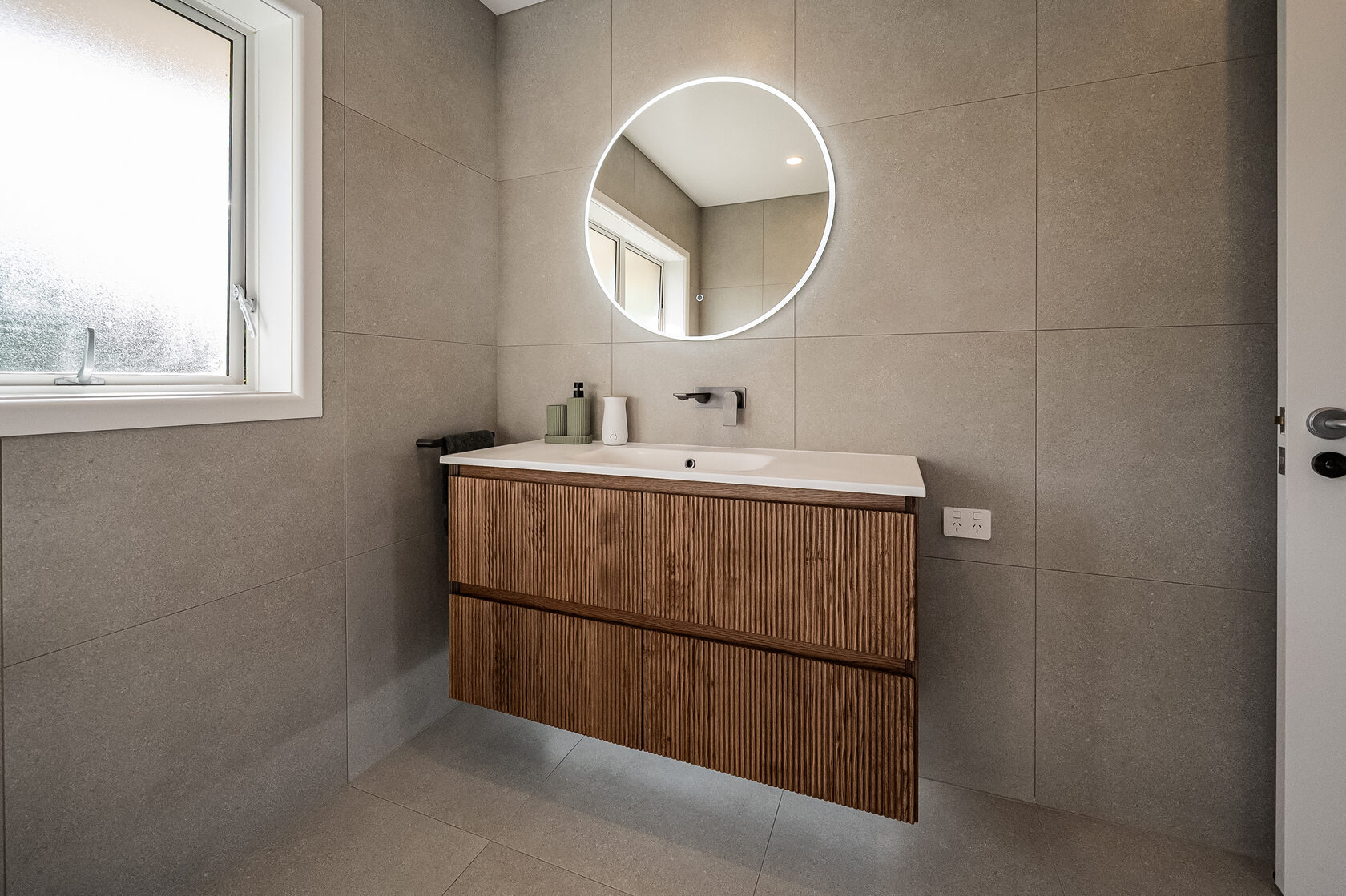 Contemporary Glenfield bathroom with grey wall tiles, timber vanity and round mirror