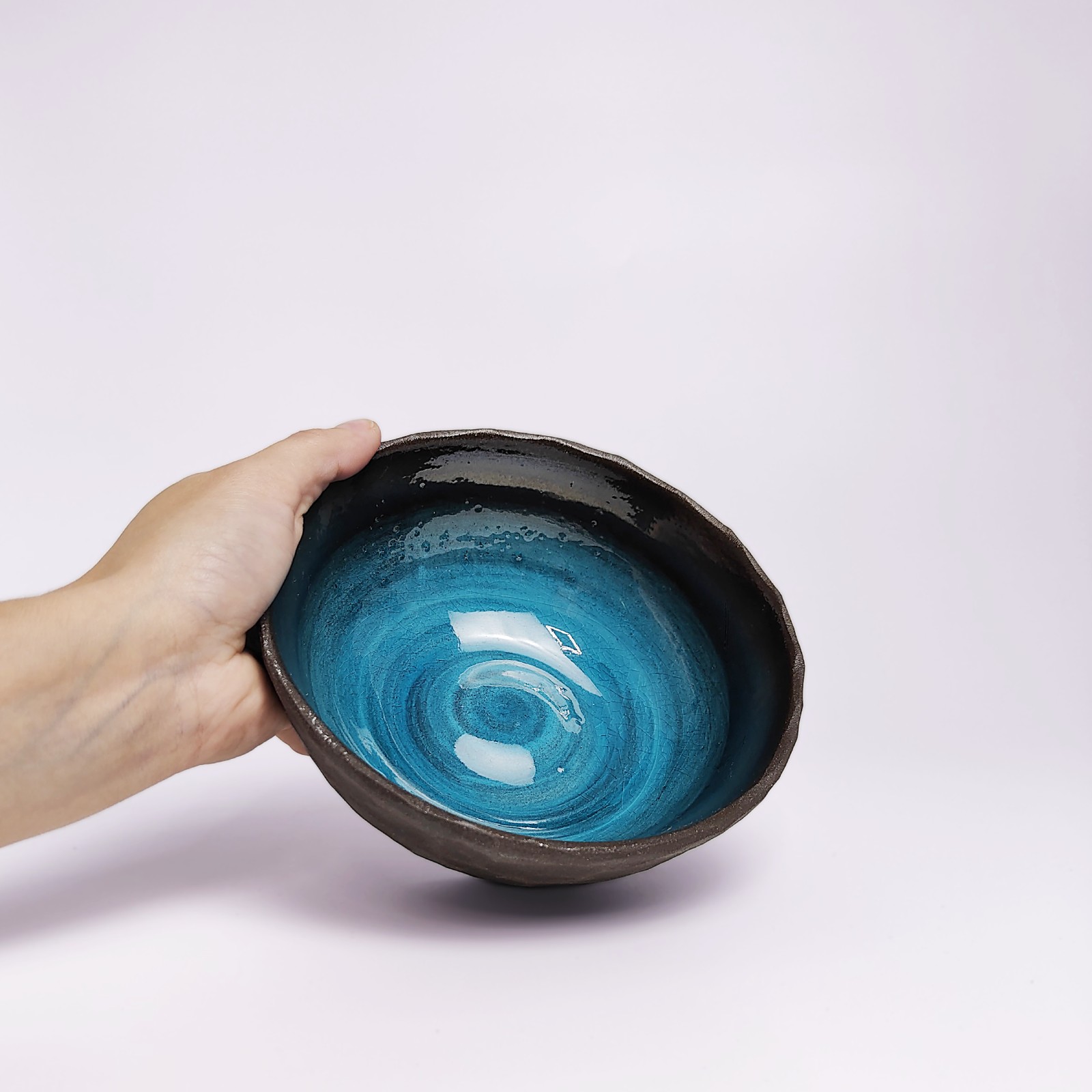 unique handmade ceramic bowl with dark clay exterior and vibrant deep blue glaze, artistic decorative tableware