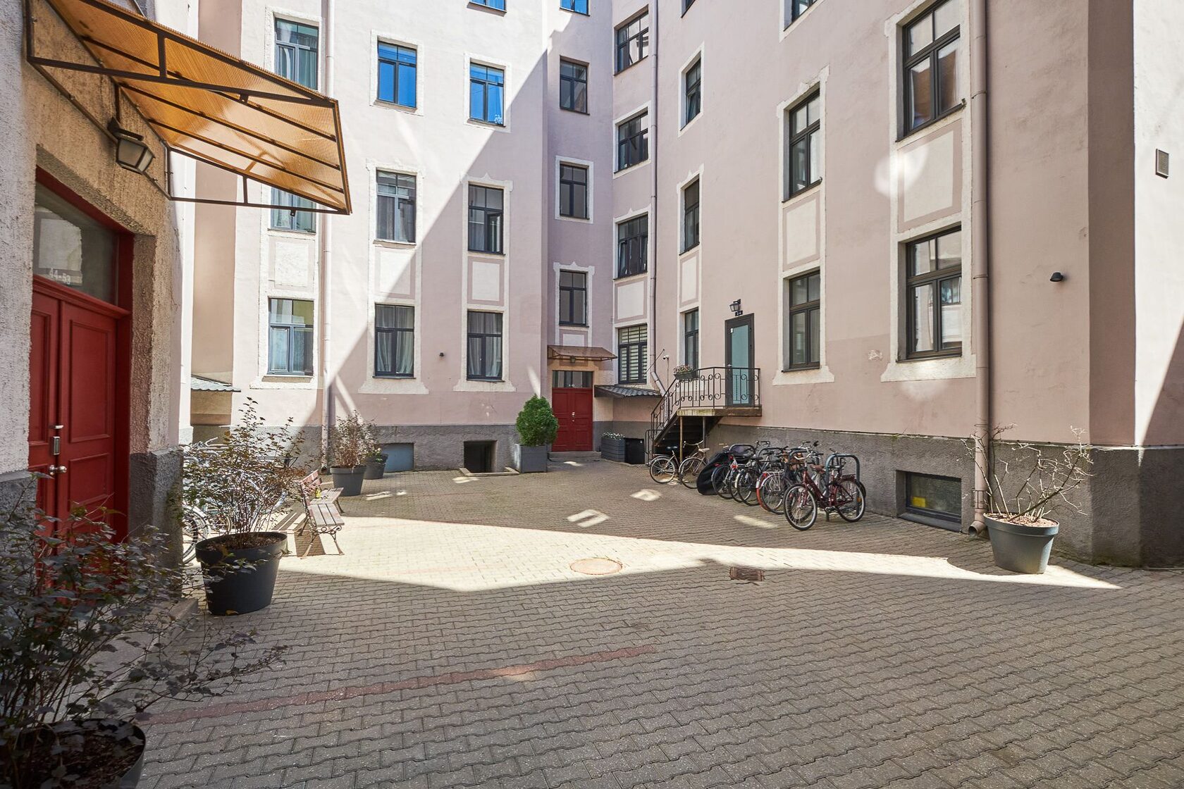 Courtyard of the renovated building at Lāčplēša iela 53, Riga — inner courtyard with red doors and greenery