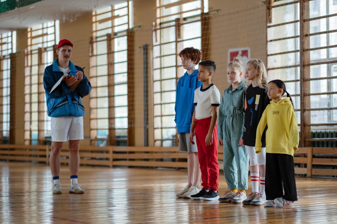 A teacher leading children in a school gym