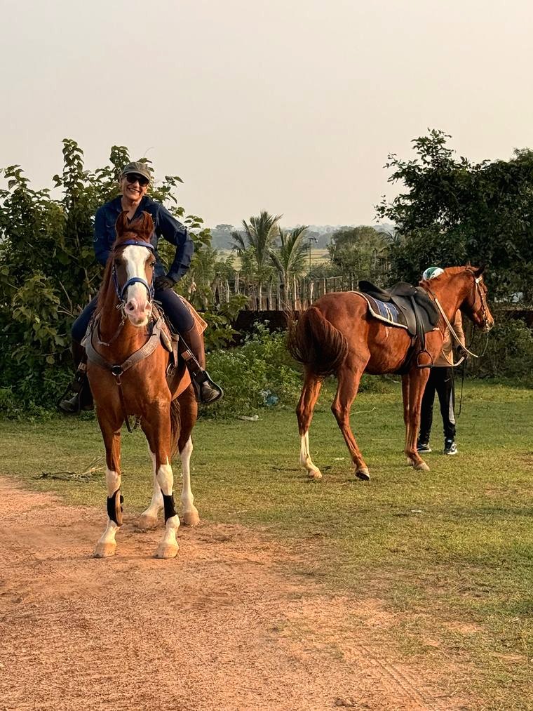 Guest on horseback at Vonfidel Ranch with saddled horses and ranch grounds in the background