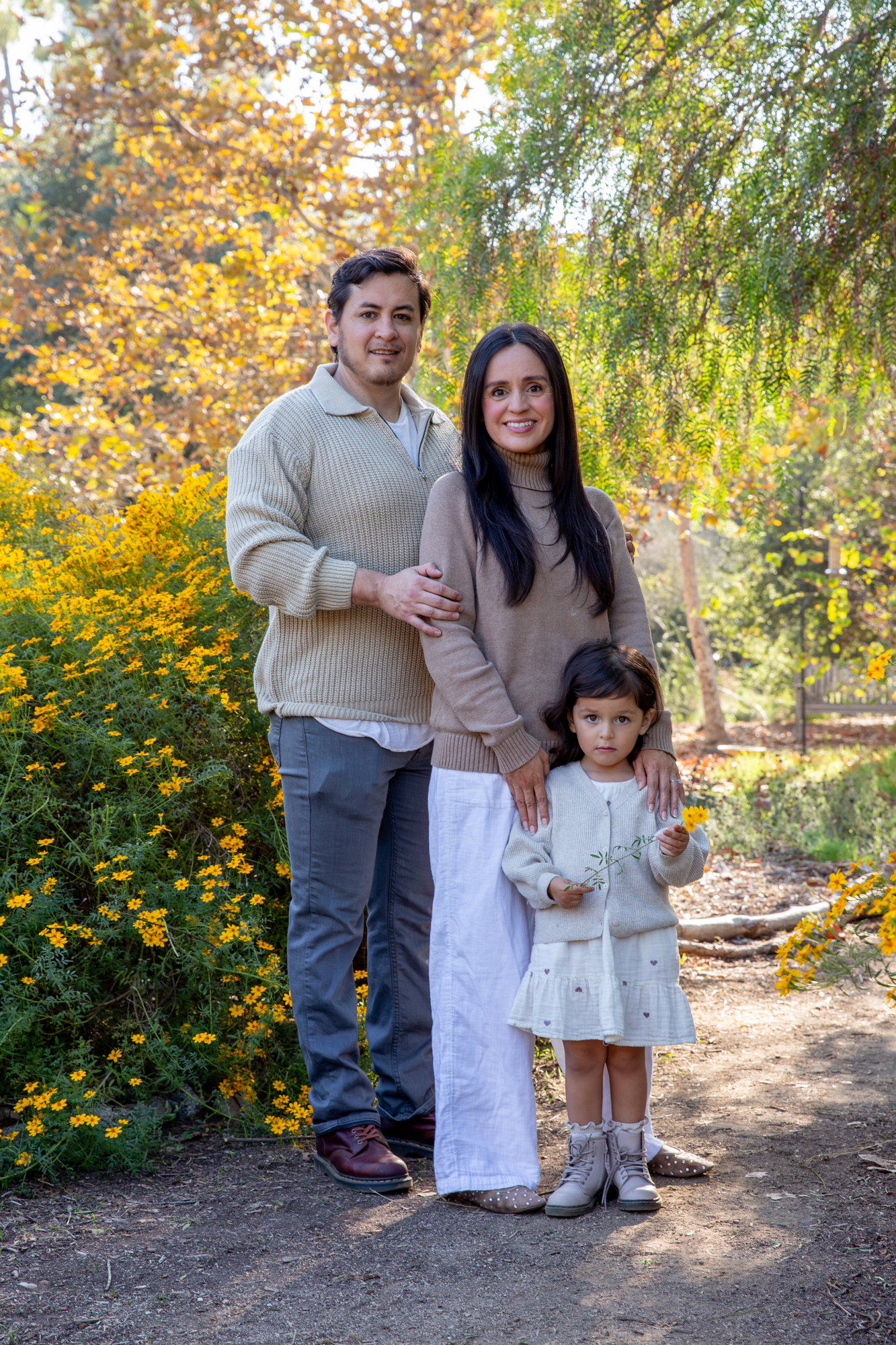 Family of three in an autumn garden with yellow flowers