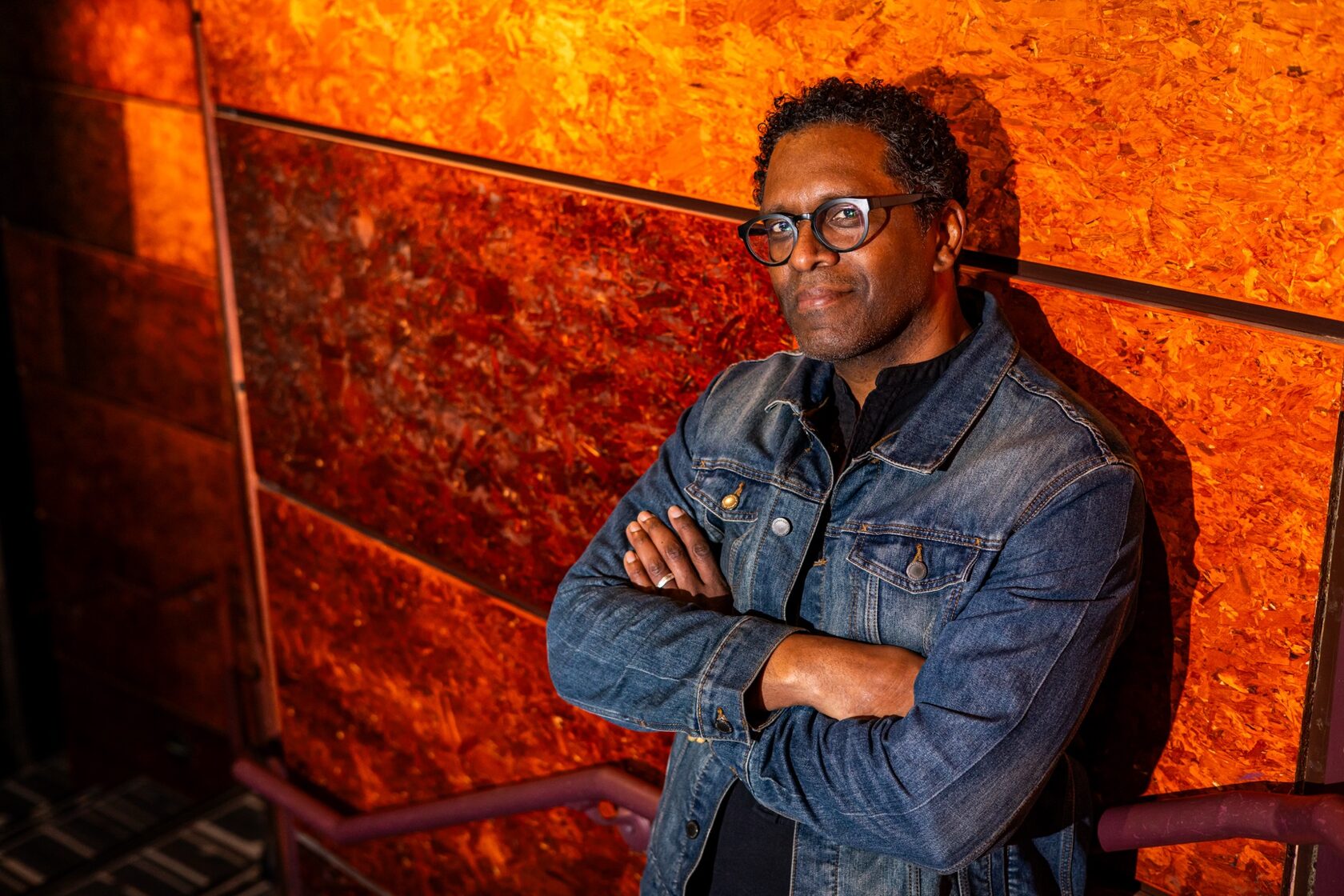 Lindsay Smiling with arms crossed against an orange wall
