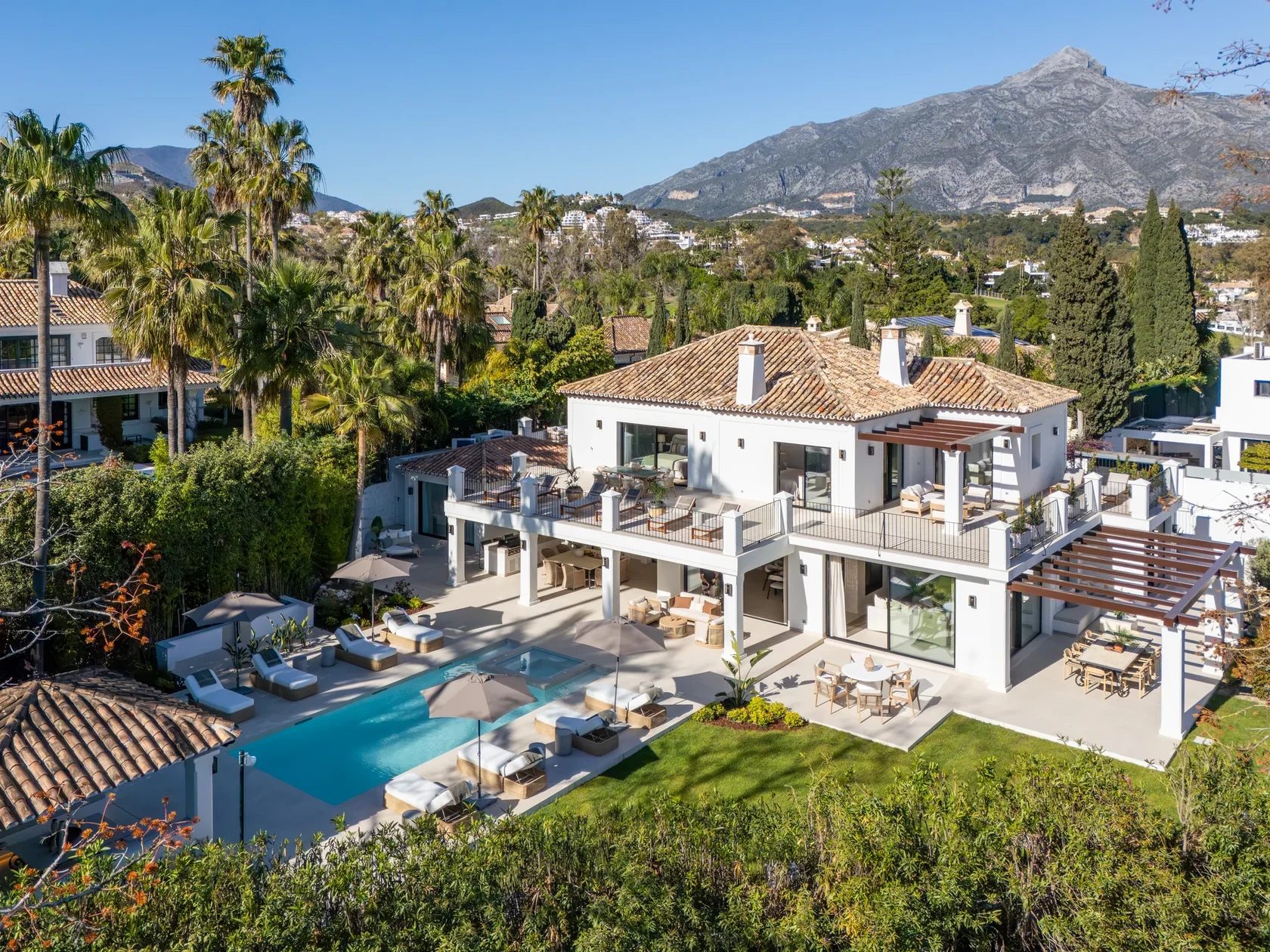 Elegant Mediterranean villa with cream facade, columns and cypress trees in Sierra Blanca