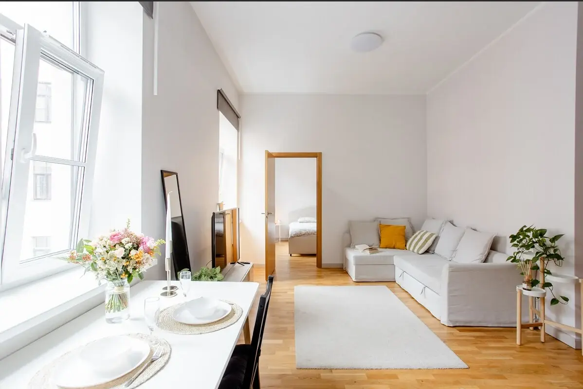 Bright living and dining area with parquet flooring and large windows at Blaumaņa iela 9A