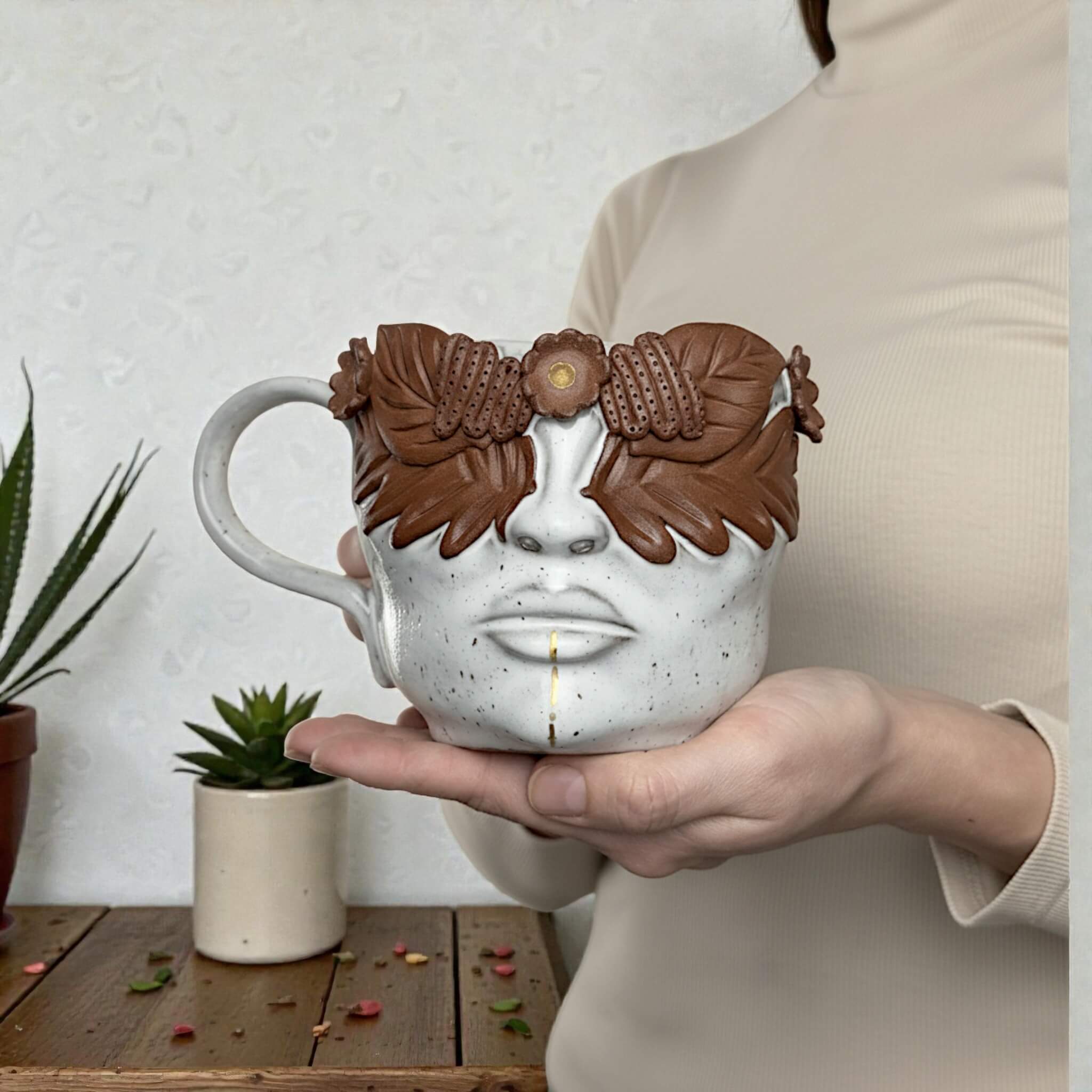 Handcrafted ceramic mug shaped like a woman's face with sculpted floral and leaf decor, artist-made unique pottery piece