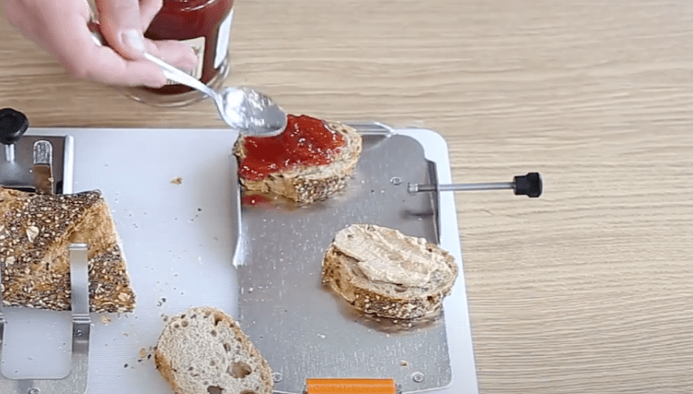 Making sandwiches using the adjustable attachment with bread stops on the adaptive cooking equipment.