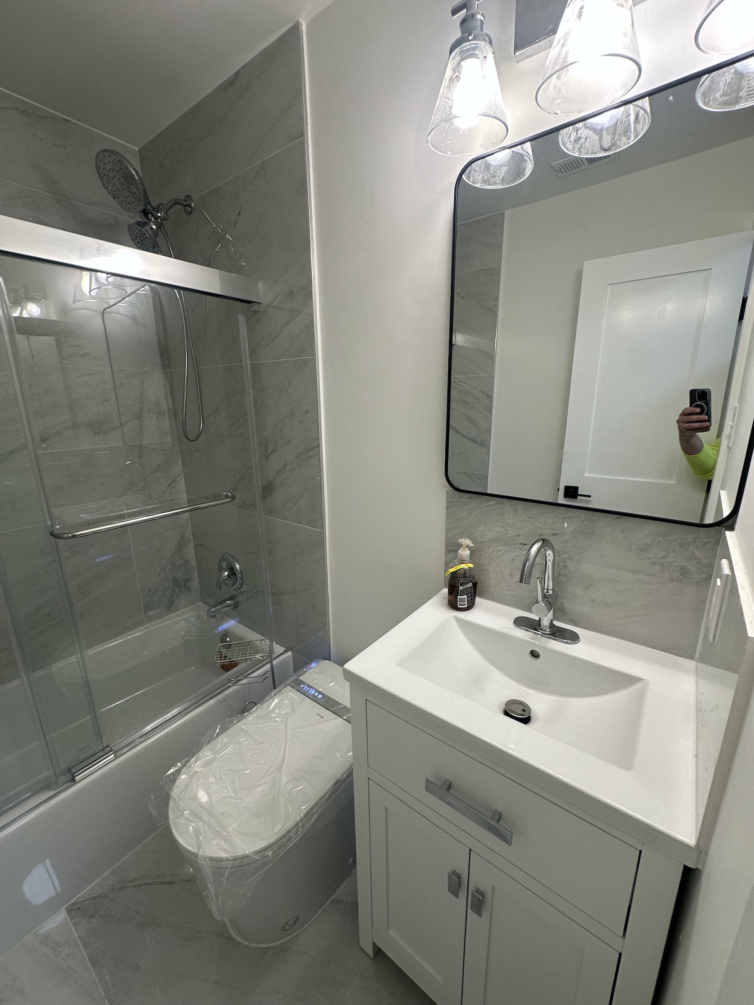 Completed full bathroom remodel in Austin with bathtub, glass panel, smart toilet, vanity and large-format tile