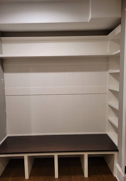 Front view of mudroom shelves and built-in dark stained bench 