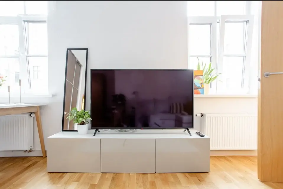 Living room with parquet flooring, large windows and fitted media unit