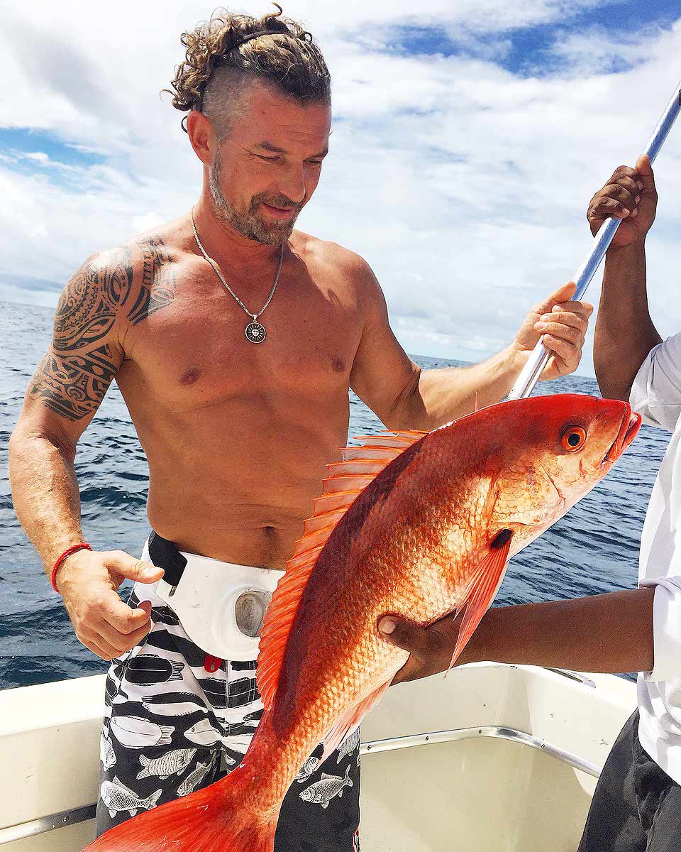 Pescador sosteniendo un gran pargo rojo en la cubierta de un bote de pesca deportiva