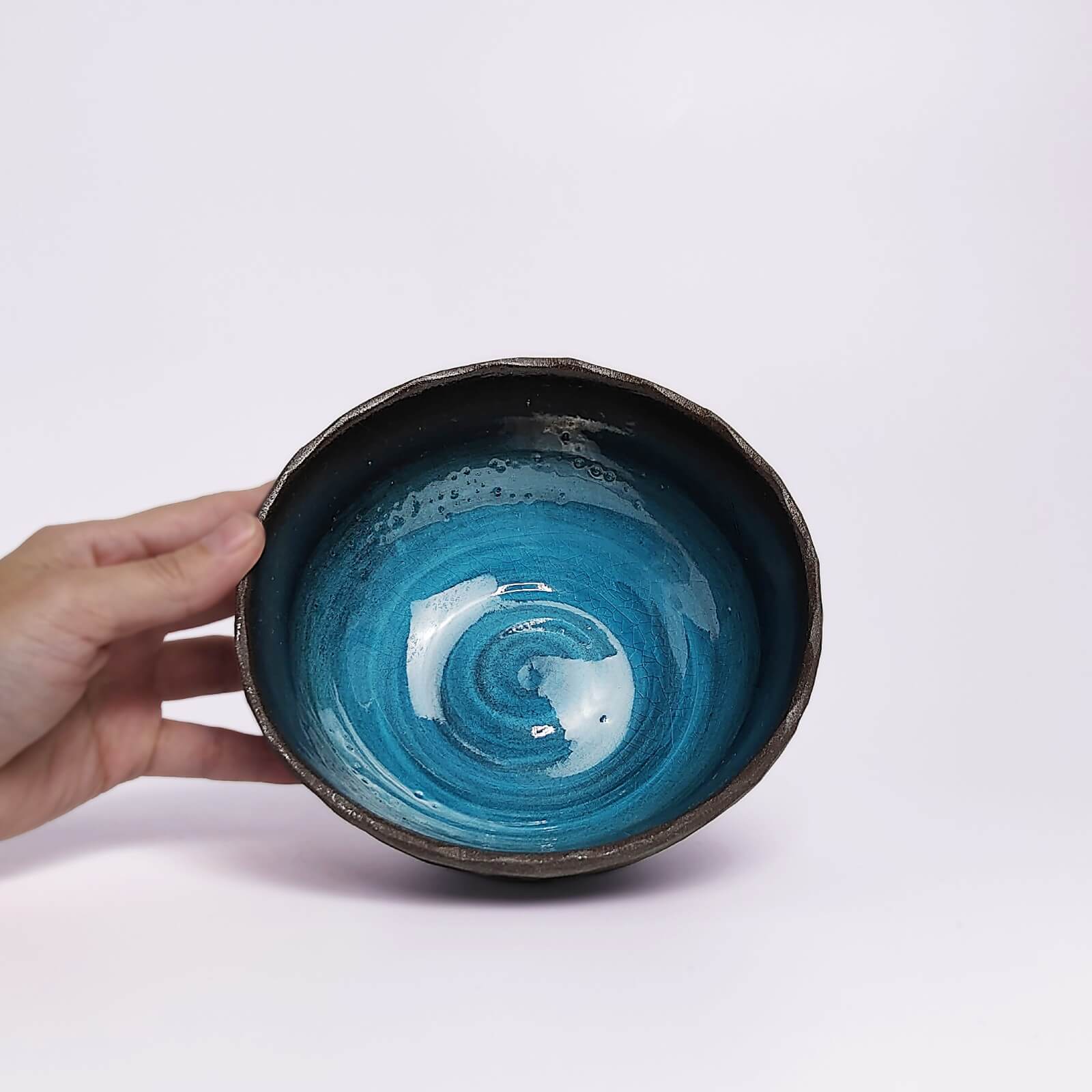 unique handmade ceramic bowl with dark clay exterior and vibrant deep blue glaze, artistic decorative tableware