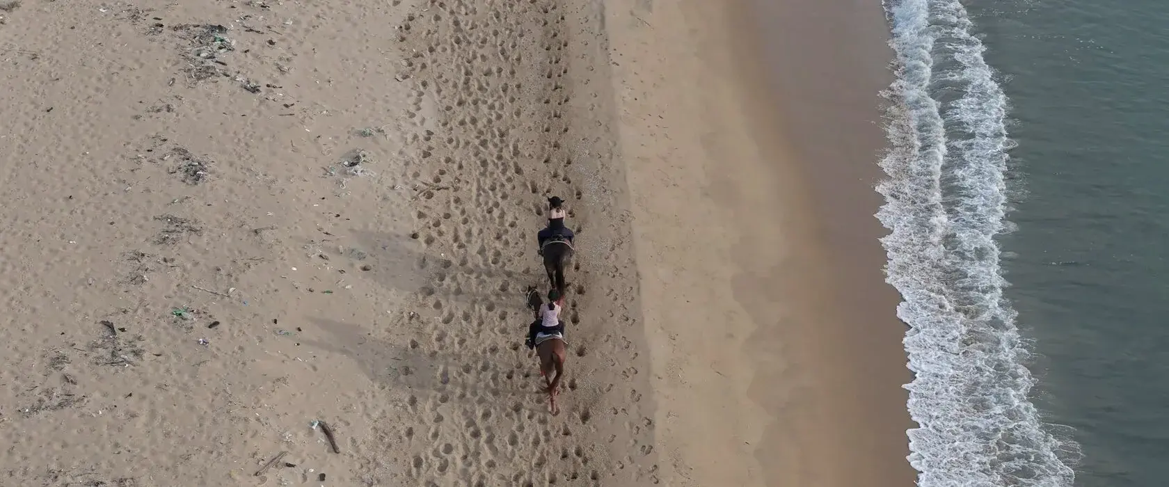 Two riders on the shore near Punanai, seen from above.
