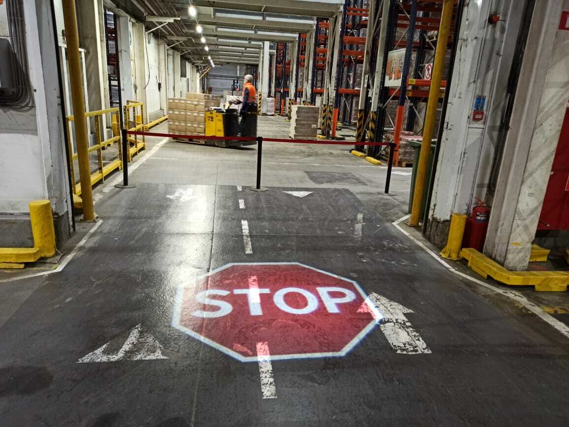 Technician aligning a projected warehouse floor marking