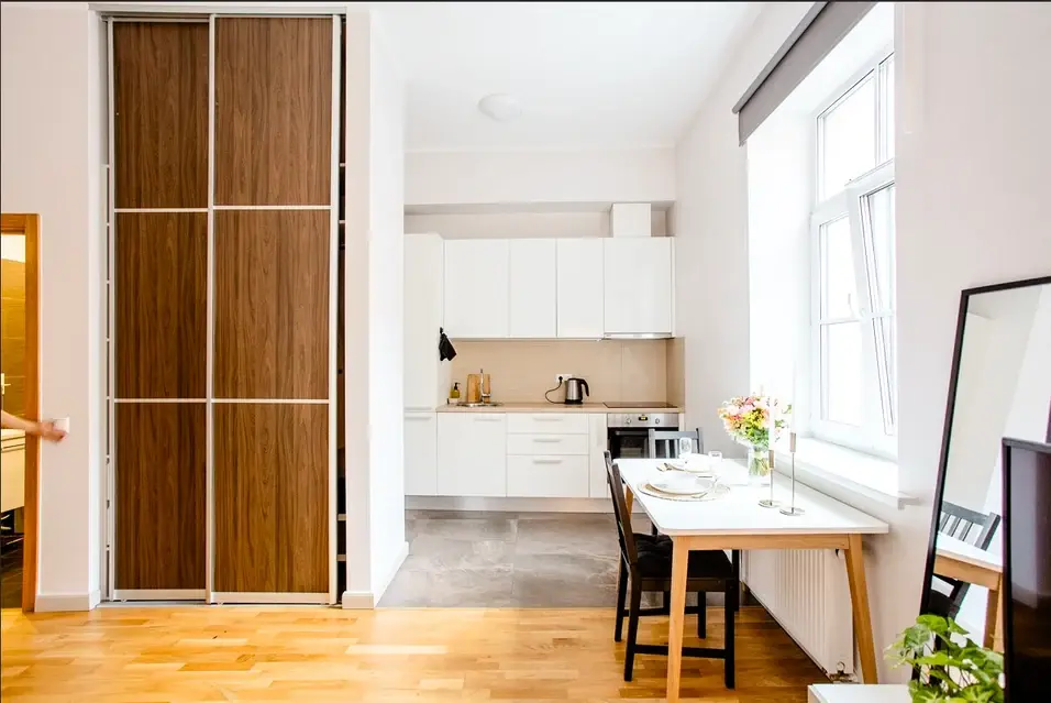 Fitted white kitchen and dining area beside large windows