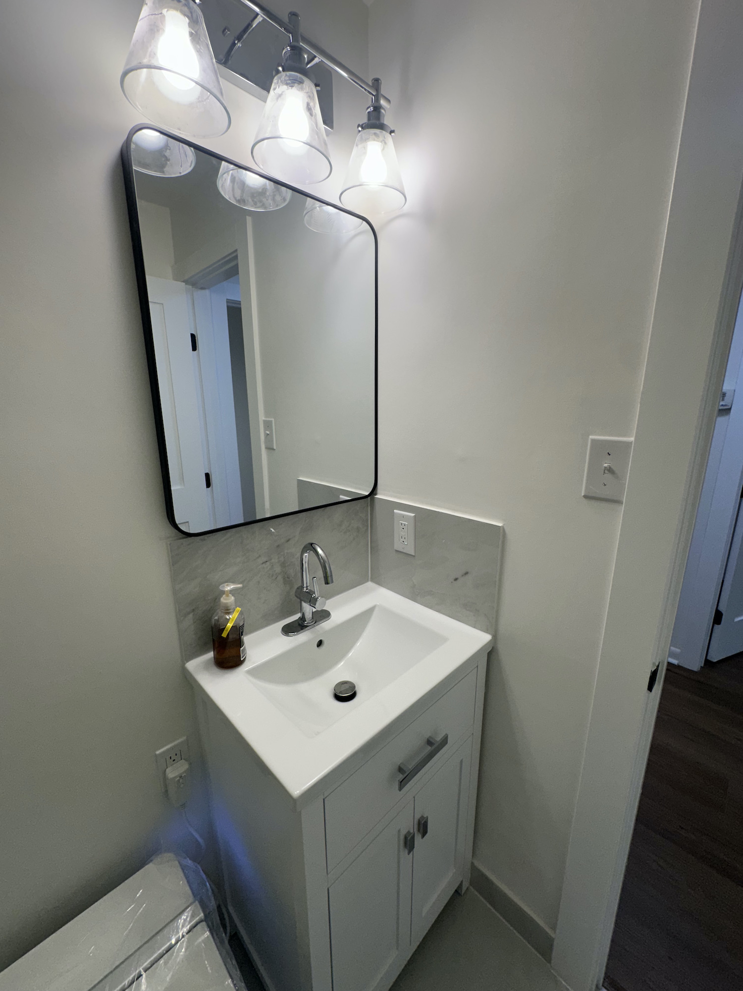 New bathroom vanity, sink, chrome faucet, mirror and wall lighting in Austin bathroom renovation
