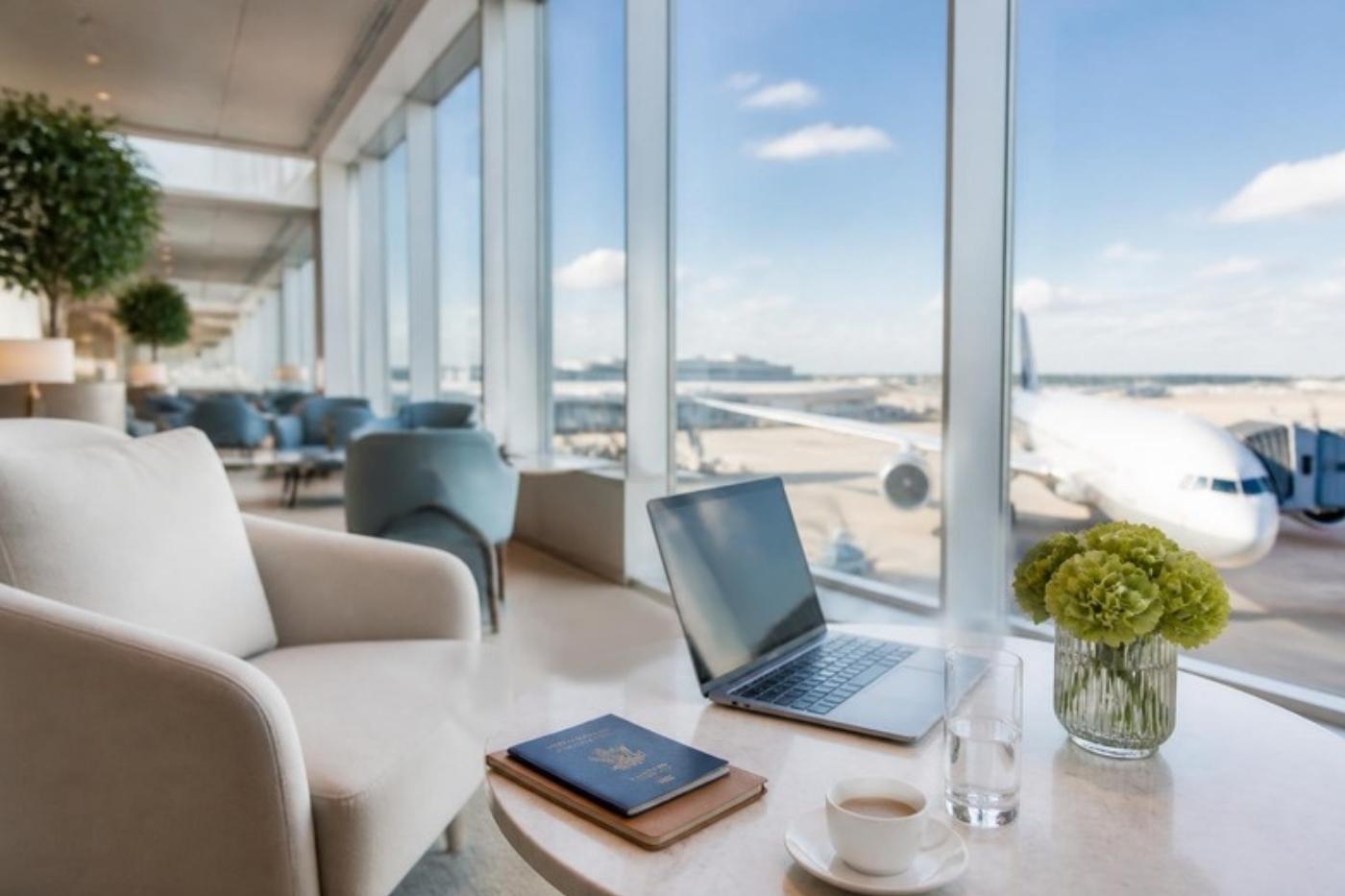 Bright airport lounge with a laptop and passport overlooking a wide-body aircraft