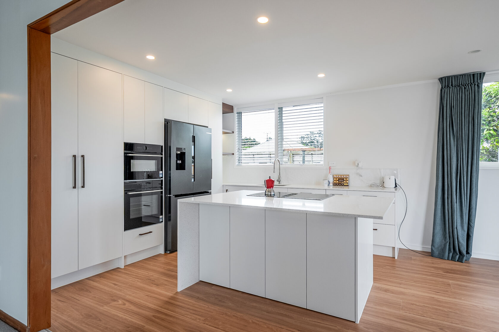 Wide view of the completed Hillcrest kitchen with white cabinetry, a large island and timber flooring