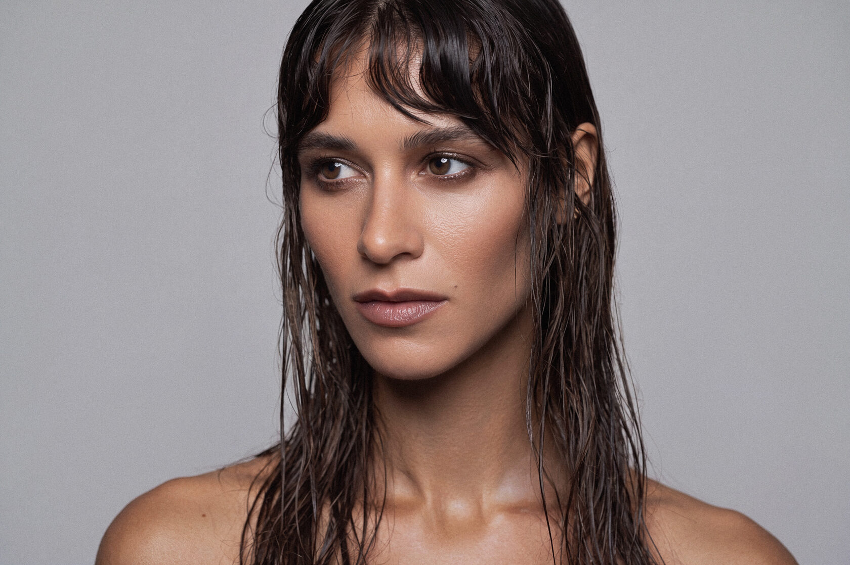 Beauty-Portrait einer Frau mit nassem Haar vor grauem Hintergrund