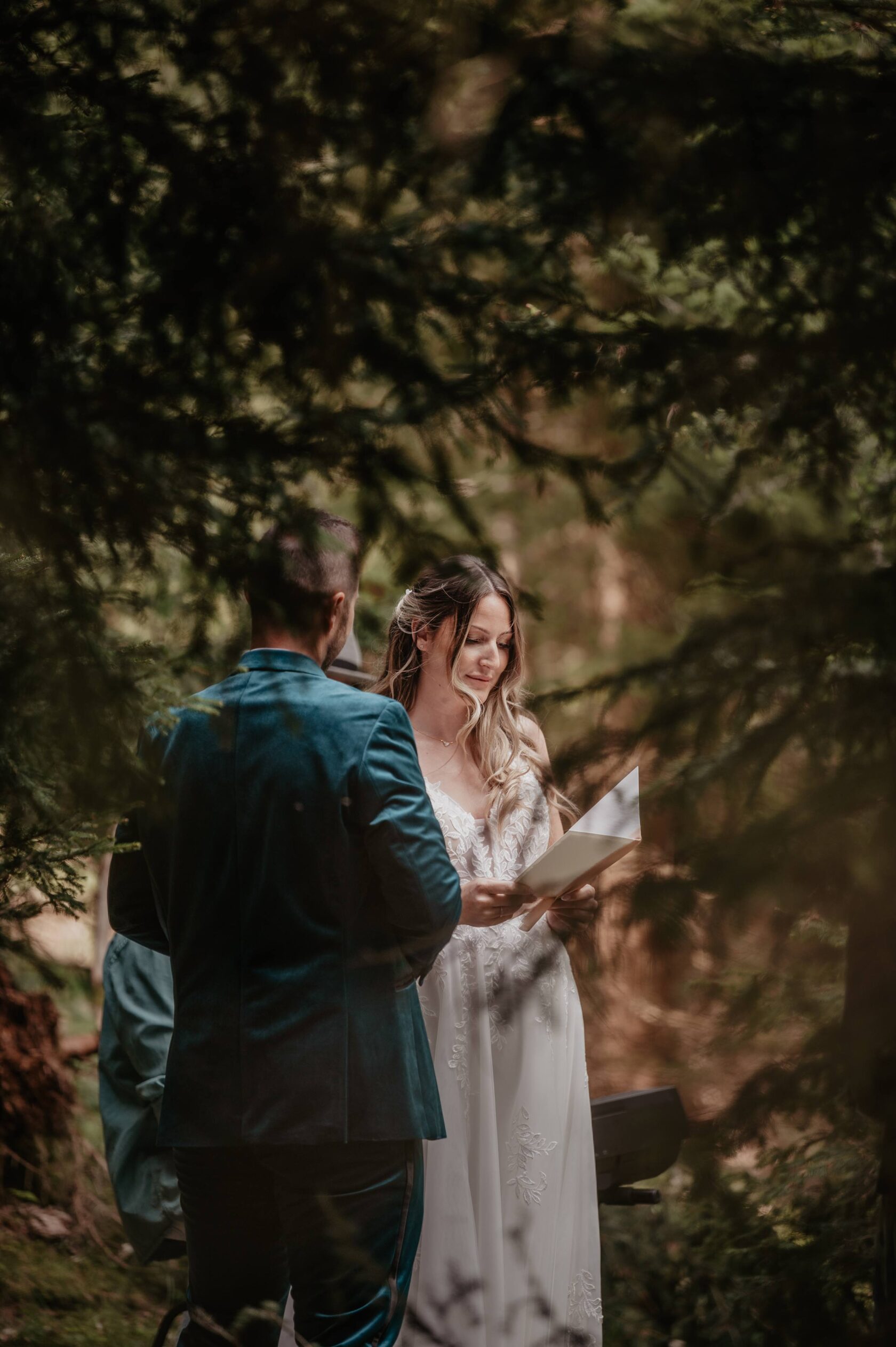 Intimate after‑wedding session in the forest — bride reading vows while groom listens quietly.