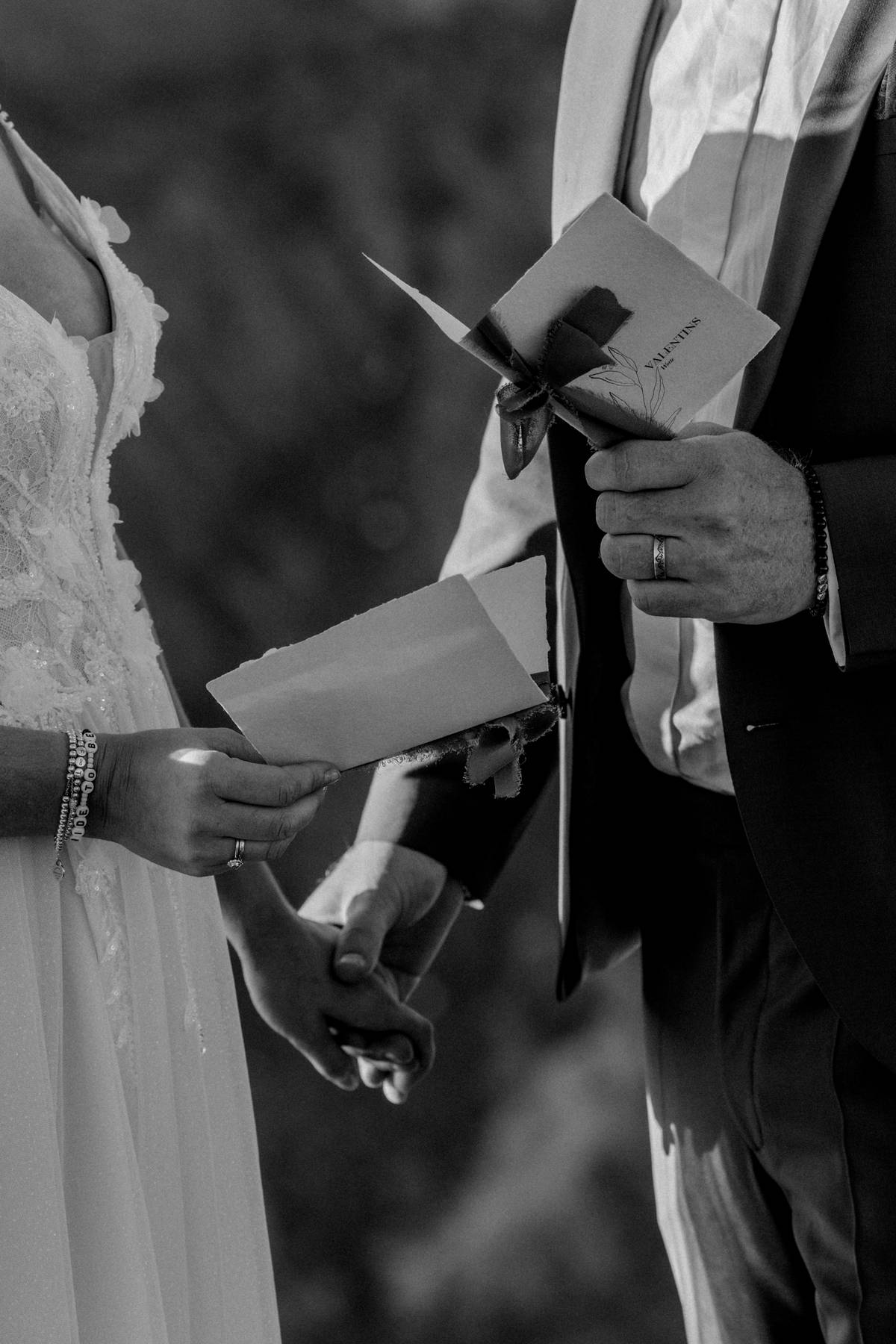 Black-and-white close-up of a couple holding vow letters during an intimate Dolomites elopement ceremony