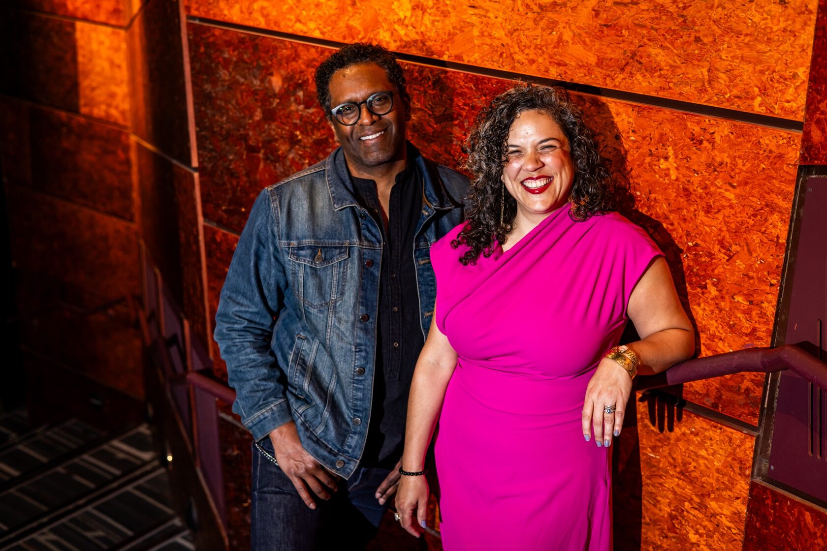 Lindsay Smiling and Leigh Goldenberg in front of an orange wall at the Wilma Theater