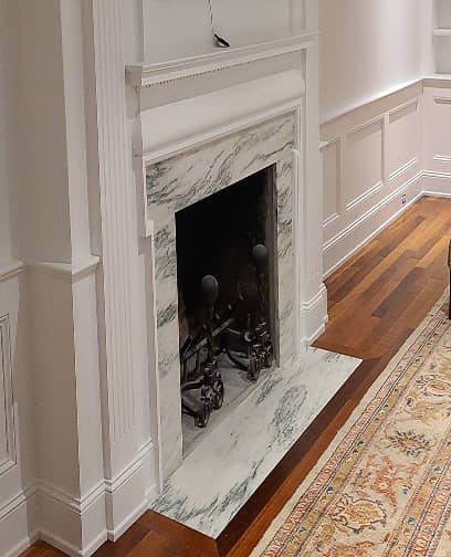 Living room fireplace with historic paneling and built-in shelves.