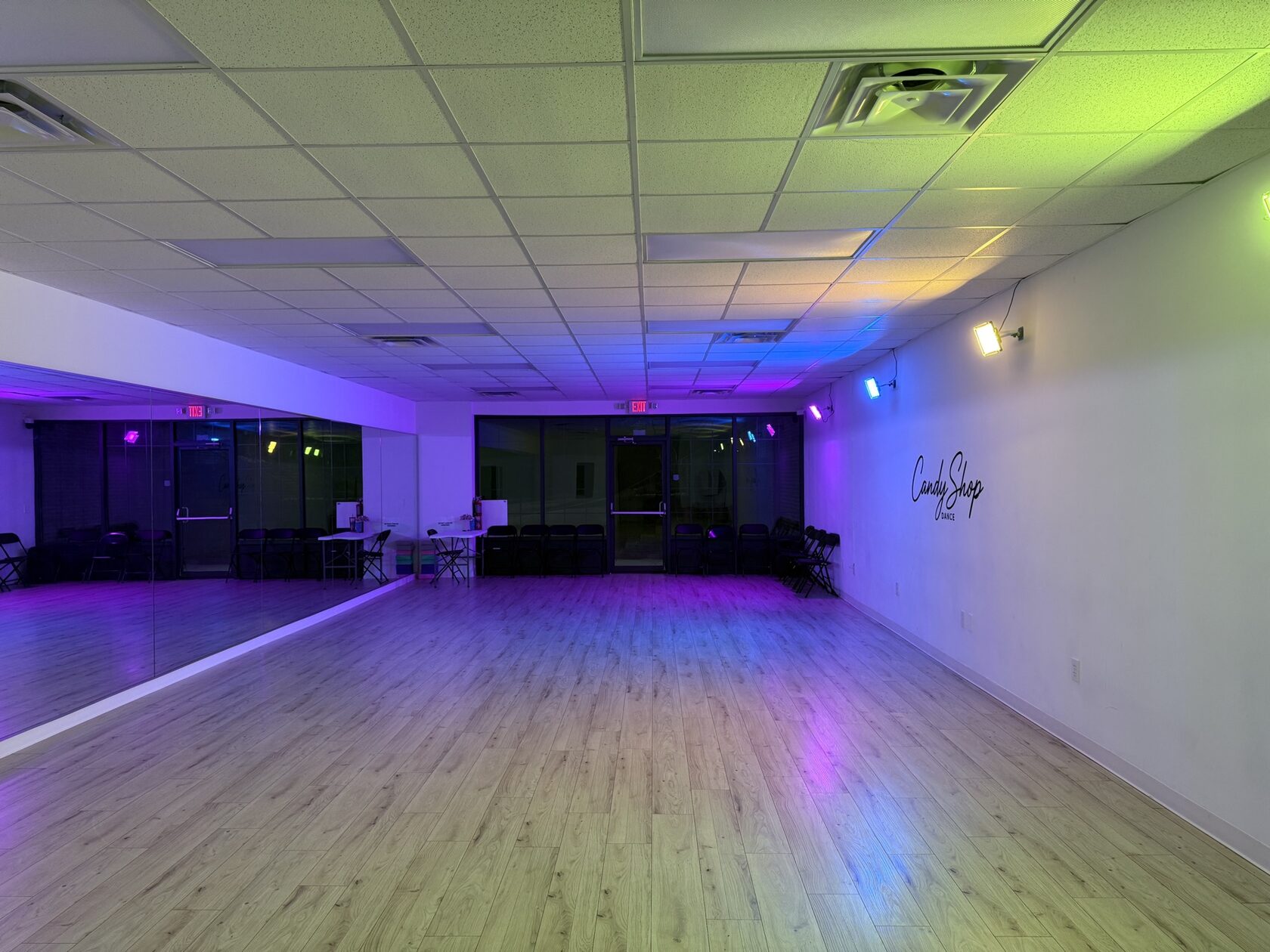 Spacious CandyShop Dance studio with wood floors, mirror wall, and colorful lighting