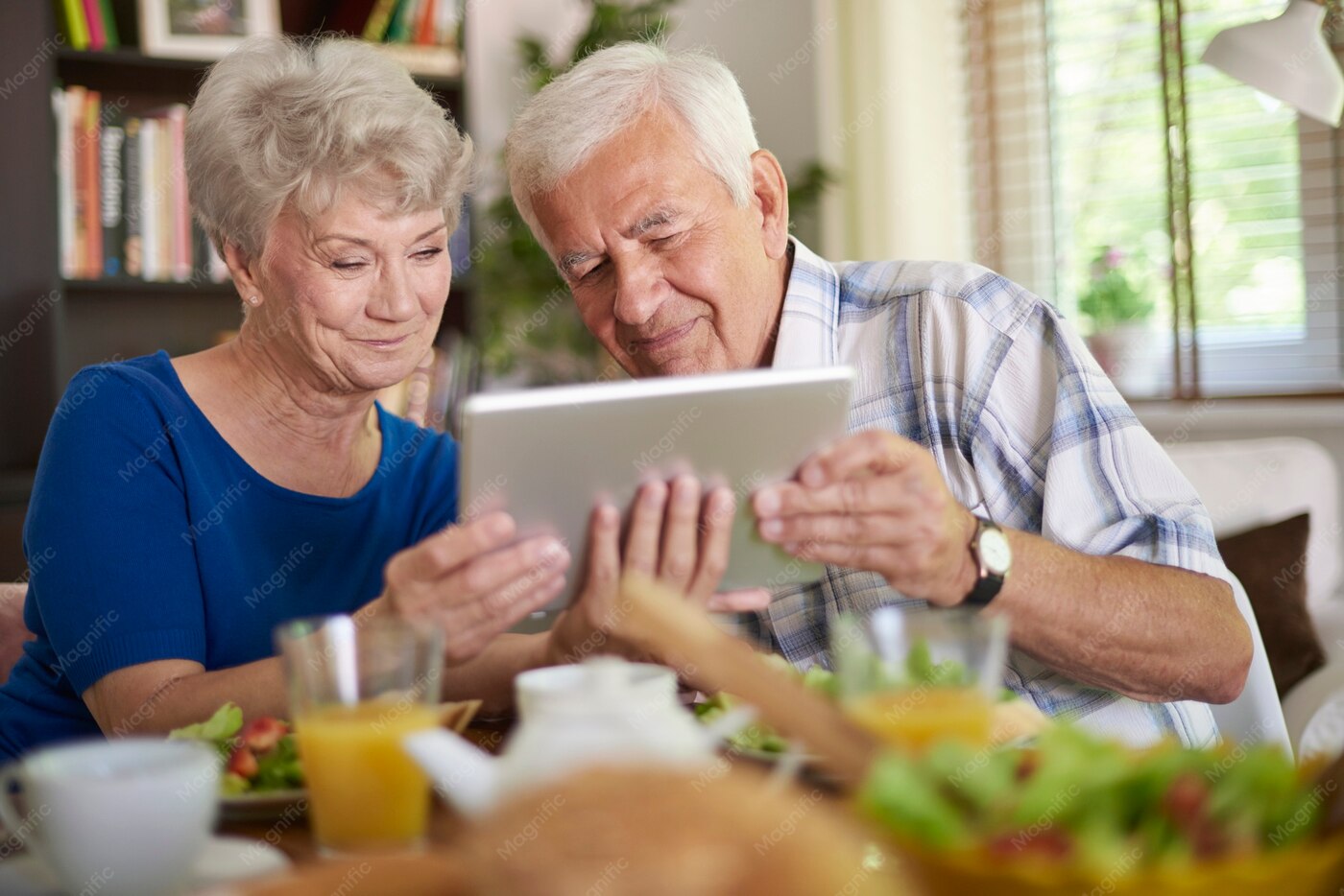 Due pensionati usano insieme un tablet a casa