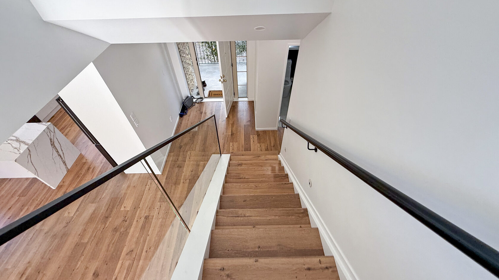 Timber staircase with glass balustrades and black handrails in St Heliers.