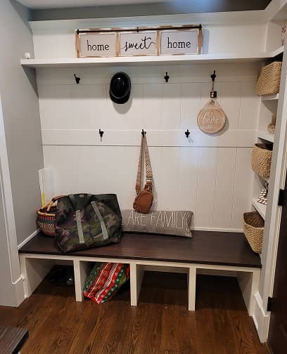Front view of mudroom shelves and built-in dark stained bench 