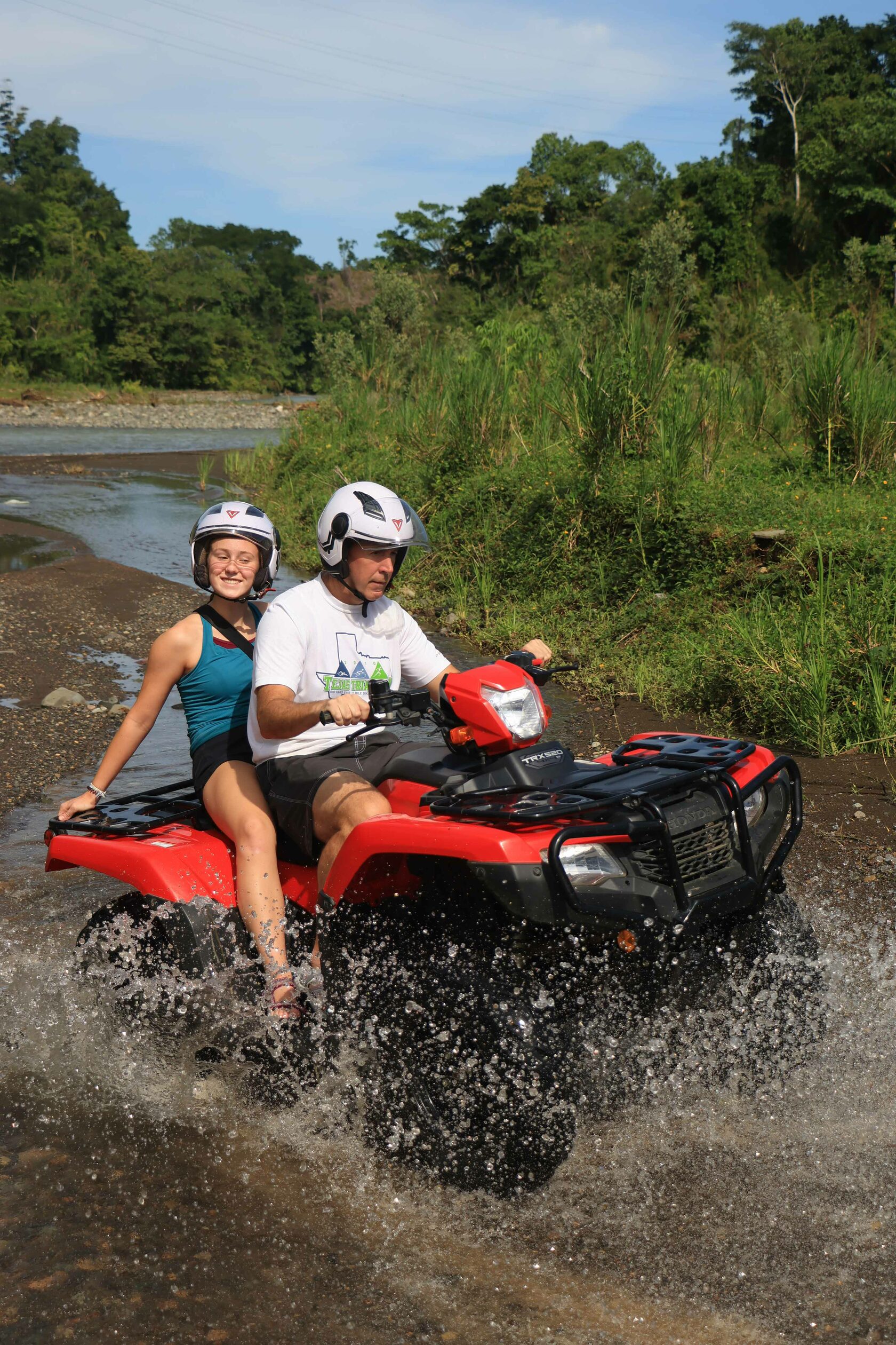 Personas cruzando un r&iacute;o en una cuatrimoto roja