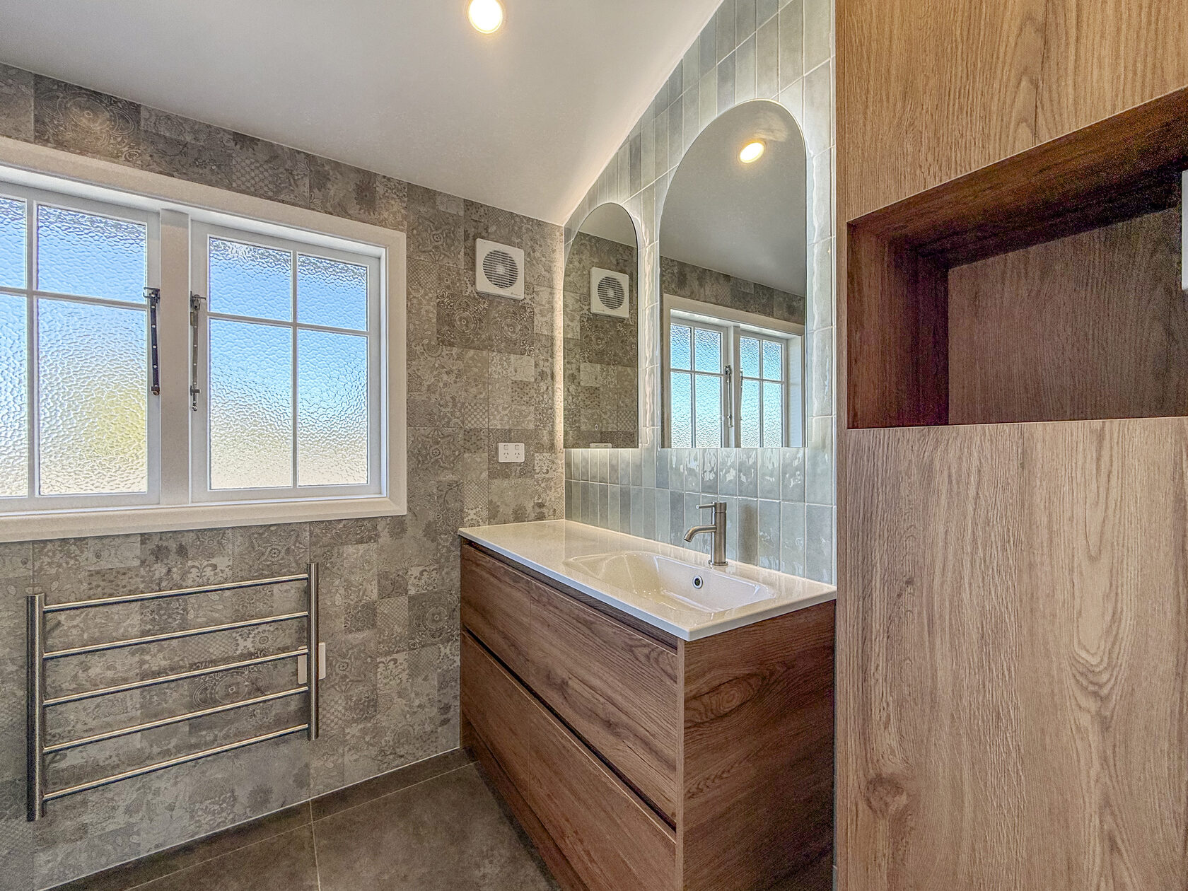 Renovated bathroom with a bath, pale vanity and illuminated round mirror