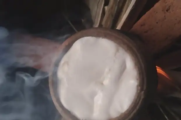 A clay pot boiling over a wood fire.