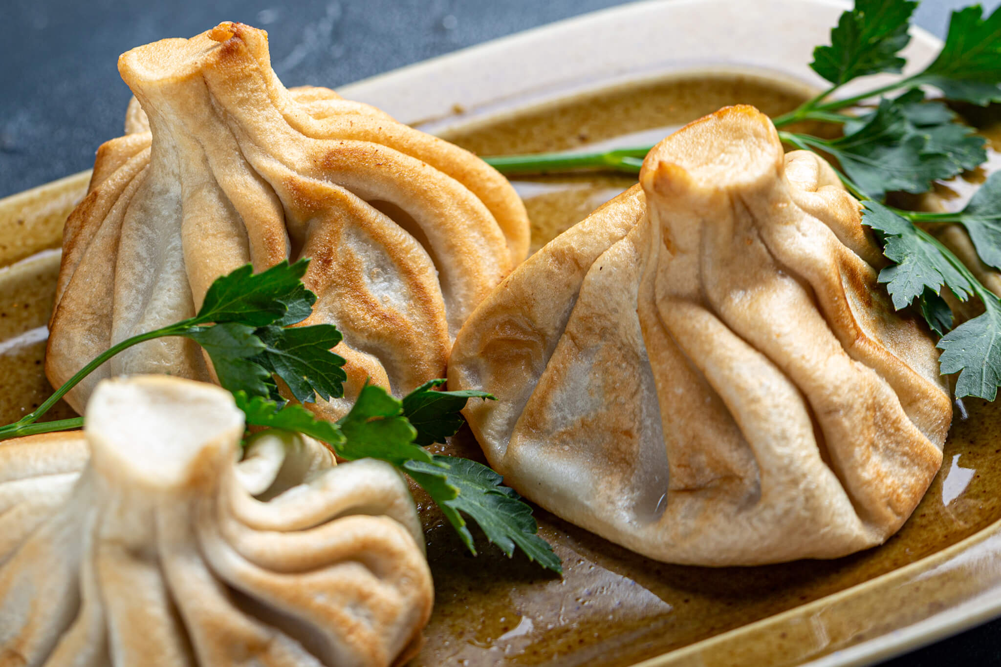 Golden pan-fried khinkali served with fresh herbs
