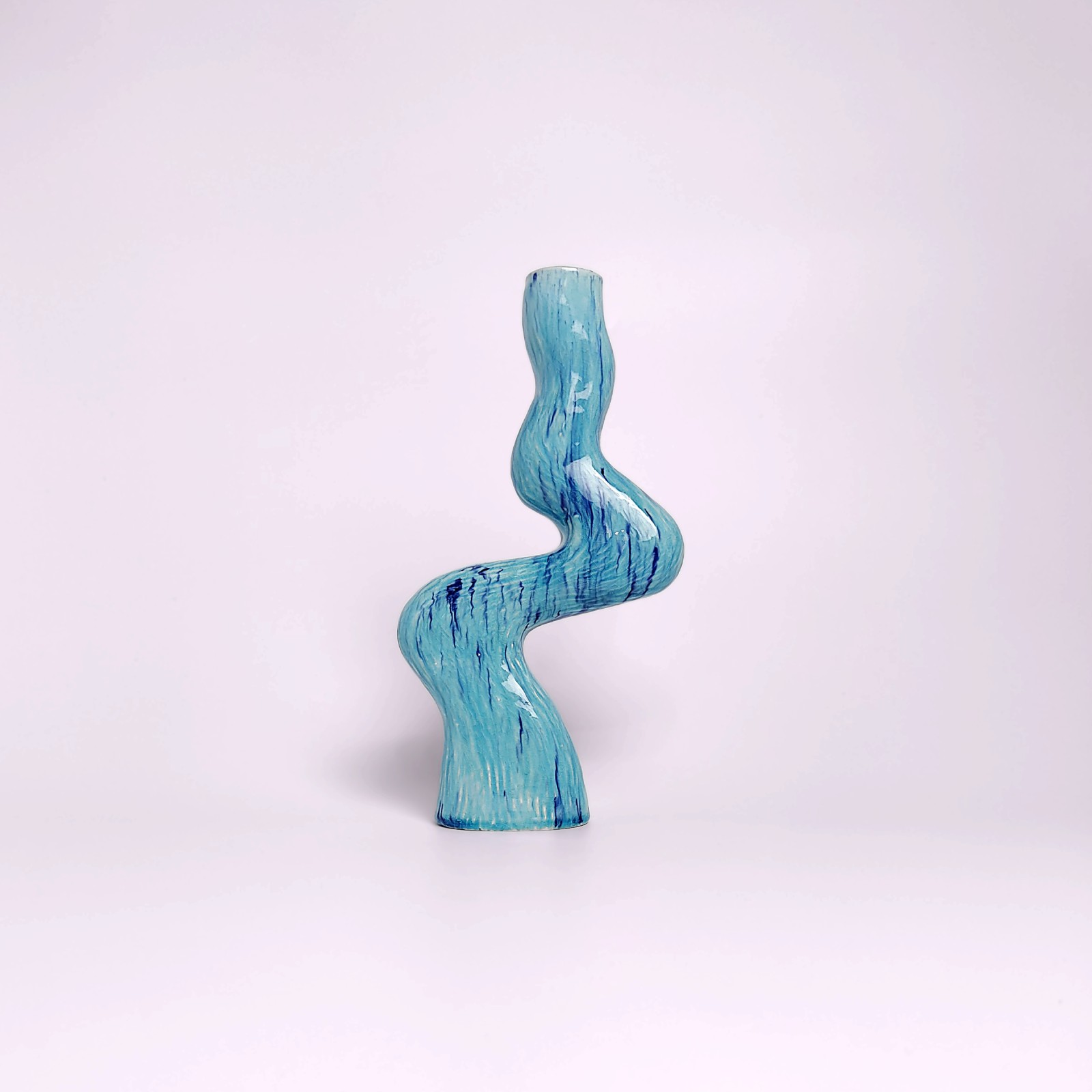 unique handmade ceramic candle holder for a single candle, featuring an organic wavy shape and blue glaze with watercolor-like drips