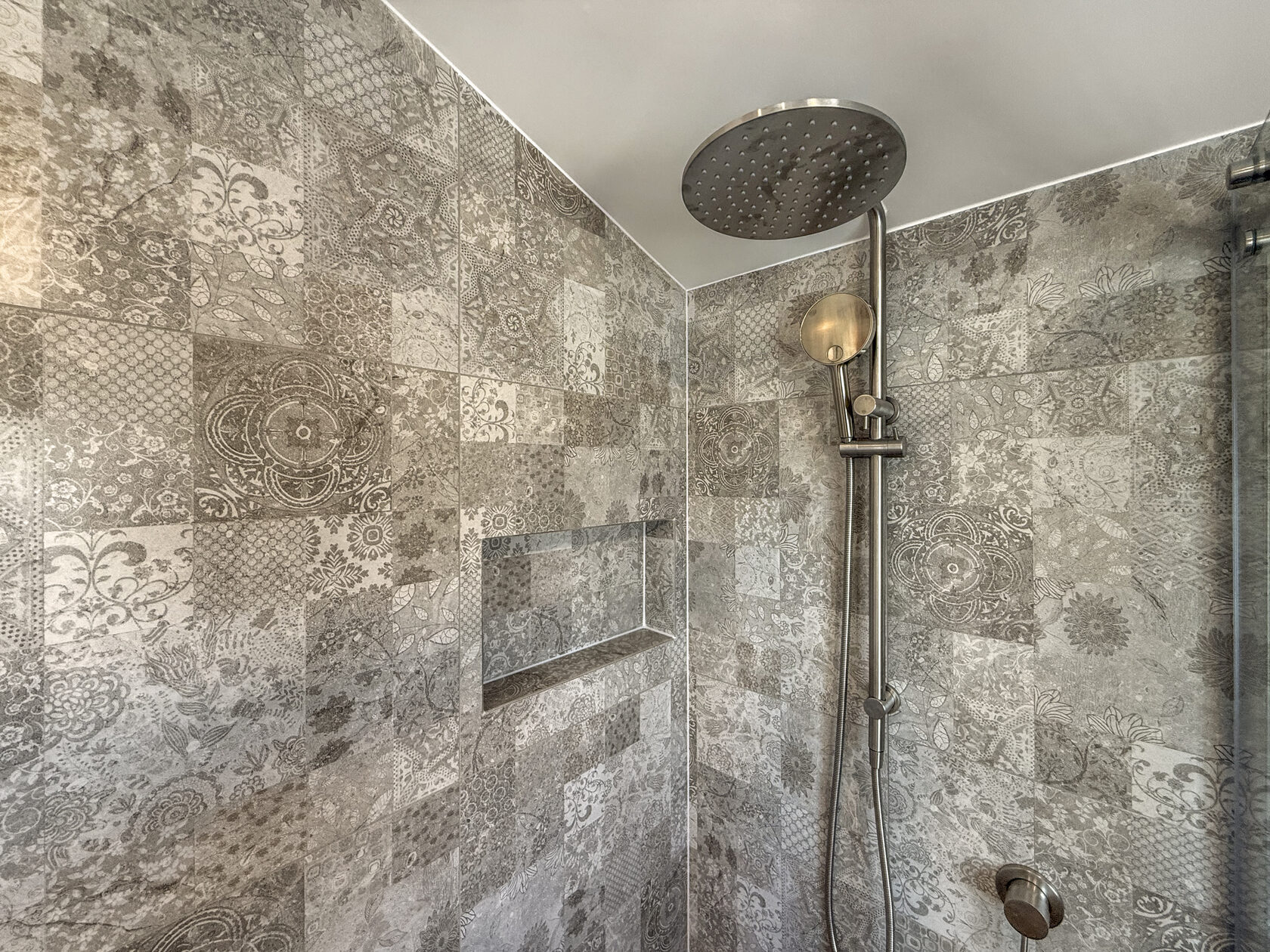 Rain shower and handheld shower against patterned grey wall tiles